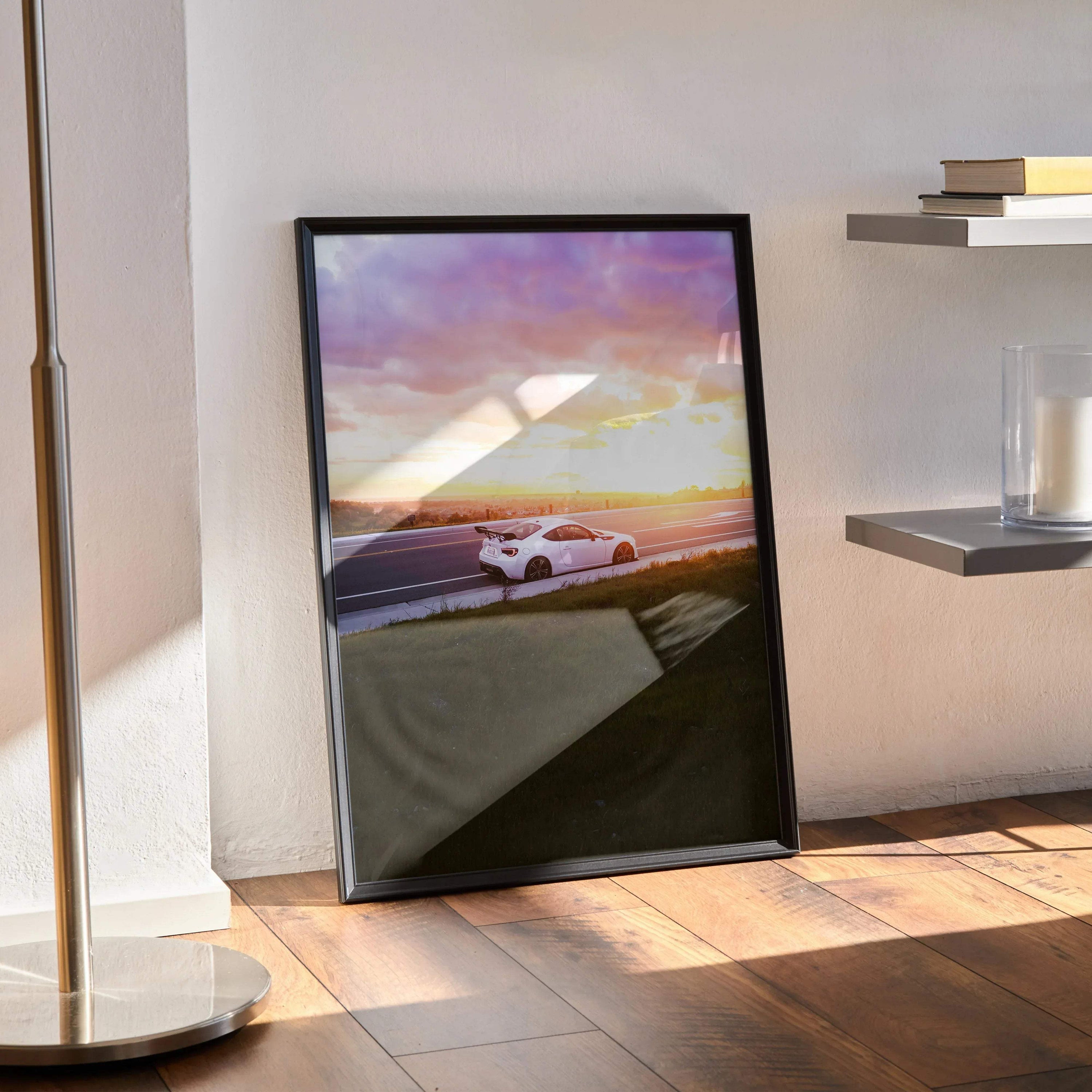 Toyota FRS car poster wall art with sunset background in black frame leaning on floor.