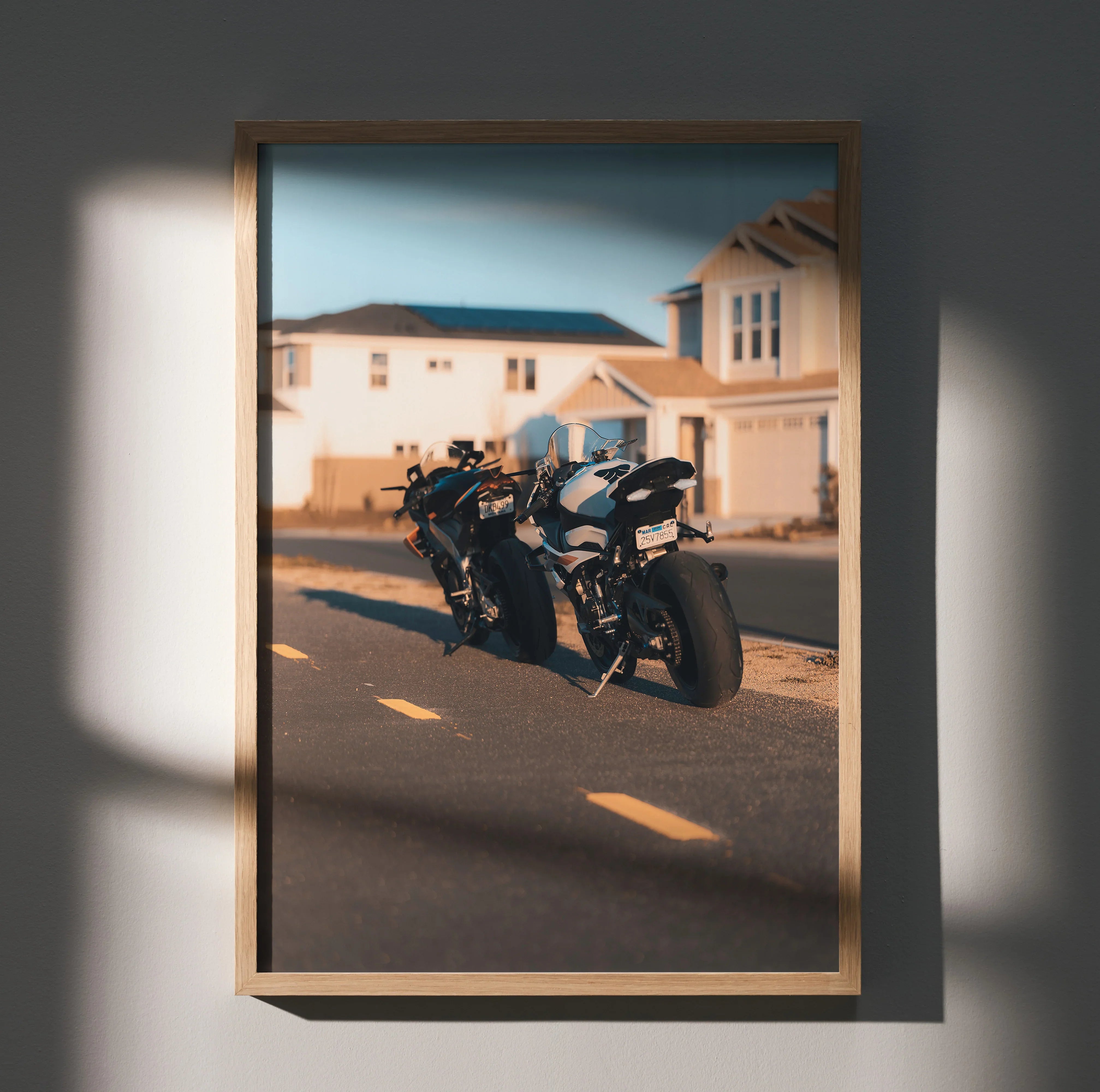 Poster wall art featuring BMW S1000RR and Aprilia RSV4 1100 motorcycles parked on suburban street at sunset.