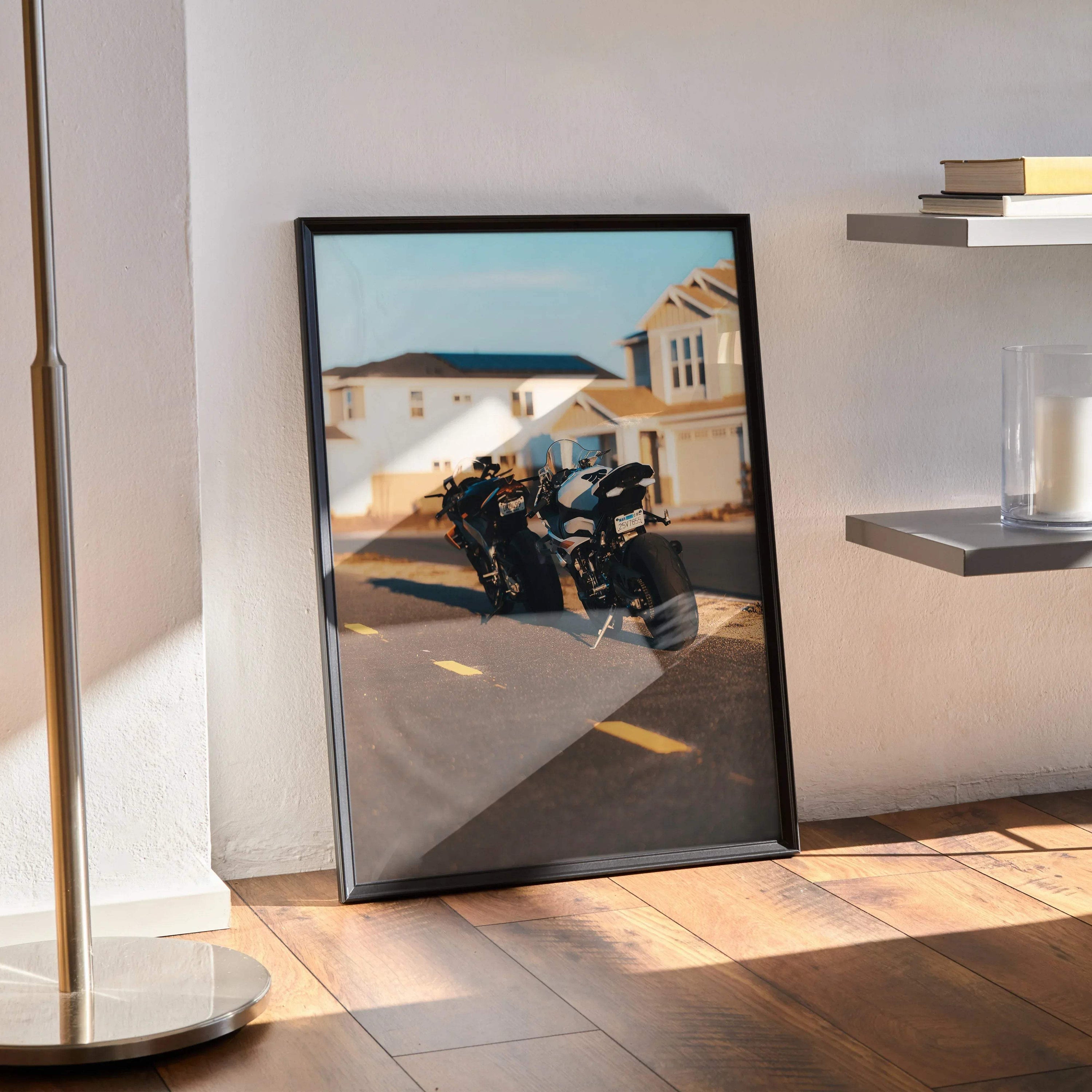 Framed poster wall art featuring BMW S1000RR and Aprilia RSV4 1100 motorcycles parked in front of suburban houses.