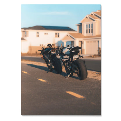 Poster wall art featuring BMW S1000RR and Aprilia RSV4 1100 motorcycles parked on a suburban street at sunset.
