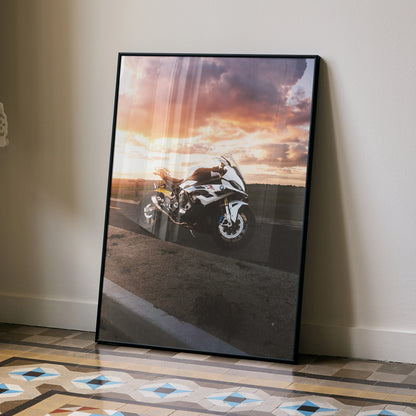 BMW S1000RR motorcycle poster with sunset background, framed wall art leaning on floor.