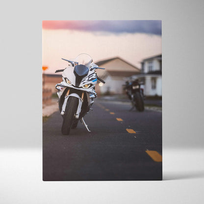 Vertical canvas art of a white BMW S1000RR motorcycle on a road at sunset with blurred background houses.