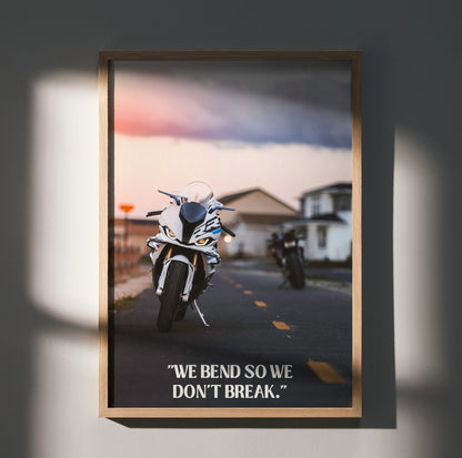 BMW S1000RR motorcycle on road with motivational text "We bend so we don't break" poster wall art in wooden frame.