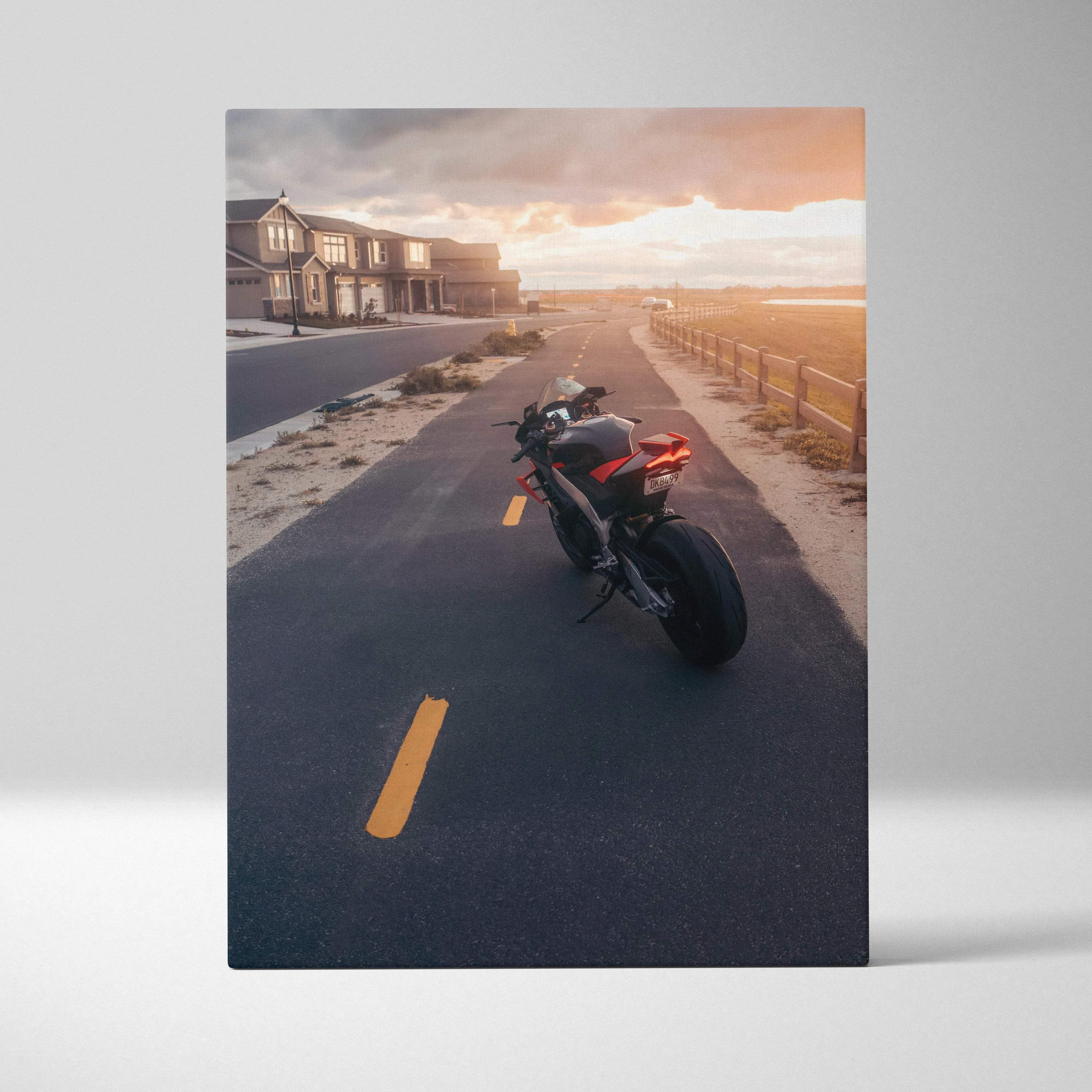 Canvas wall art featuring a black and red Aprilia RSV4 1100 Factory motorcycle with sleek design at sunset on a suburban road