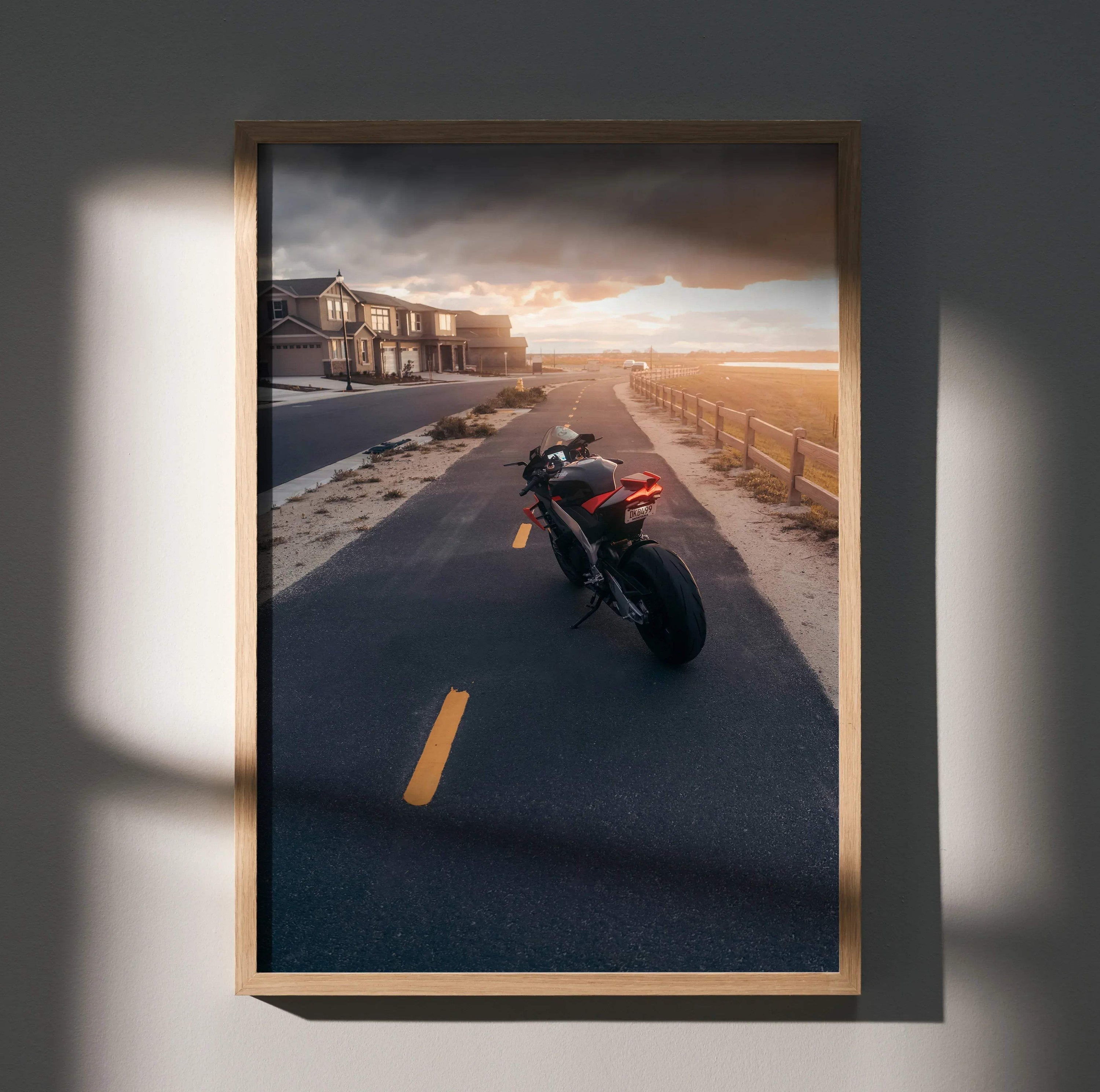 Aprilia RSV4 1100 Factory motorcycle on coastal road at sunset poster wall art in wooden frame.
