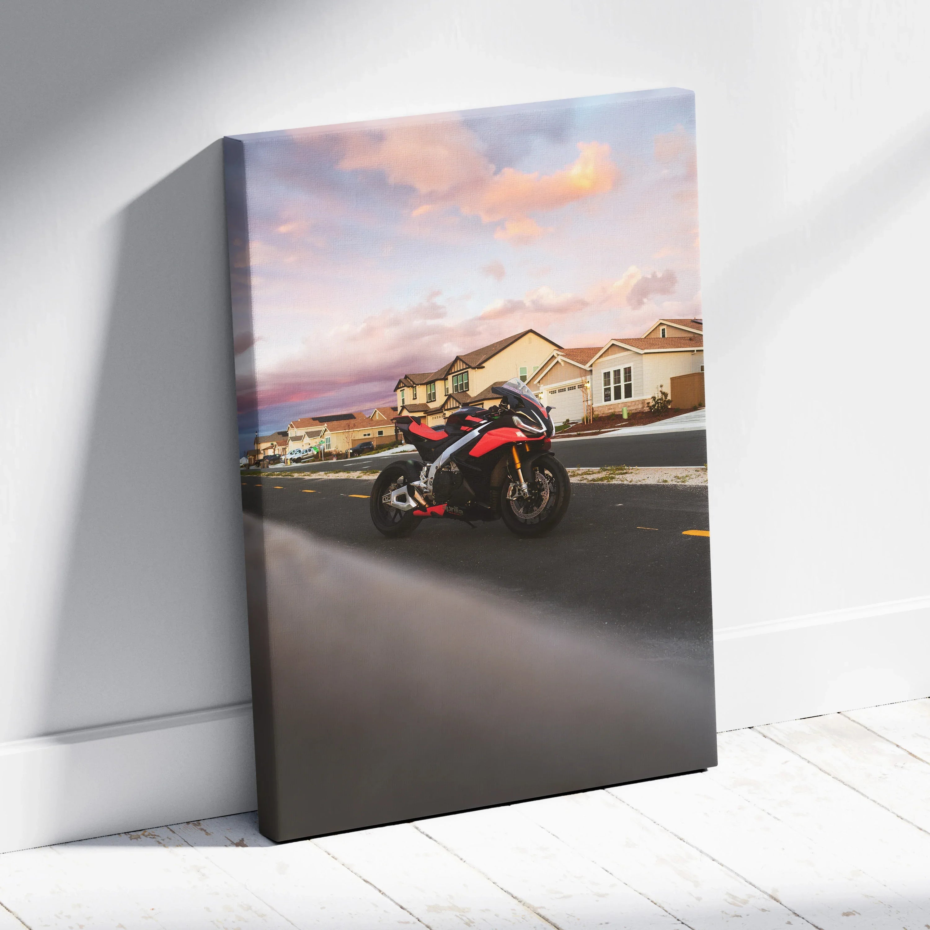 Vertical canvas wall art featuring a red and black Aprilia RSV4 motorcycle on a suburban street at sunset.