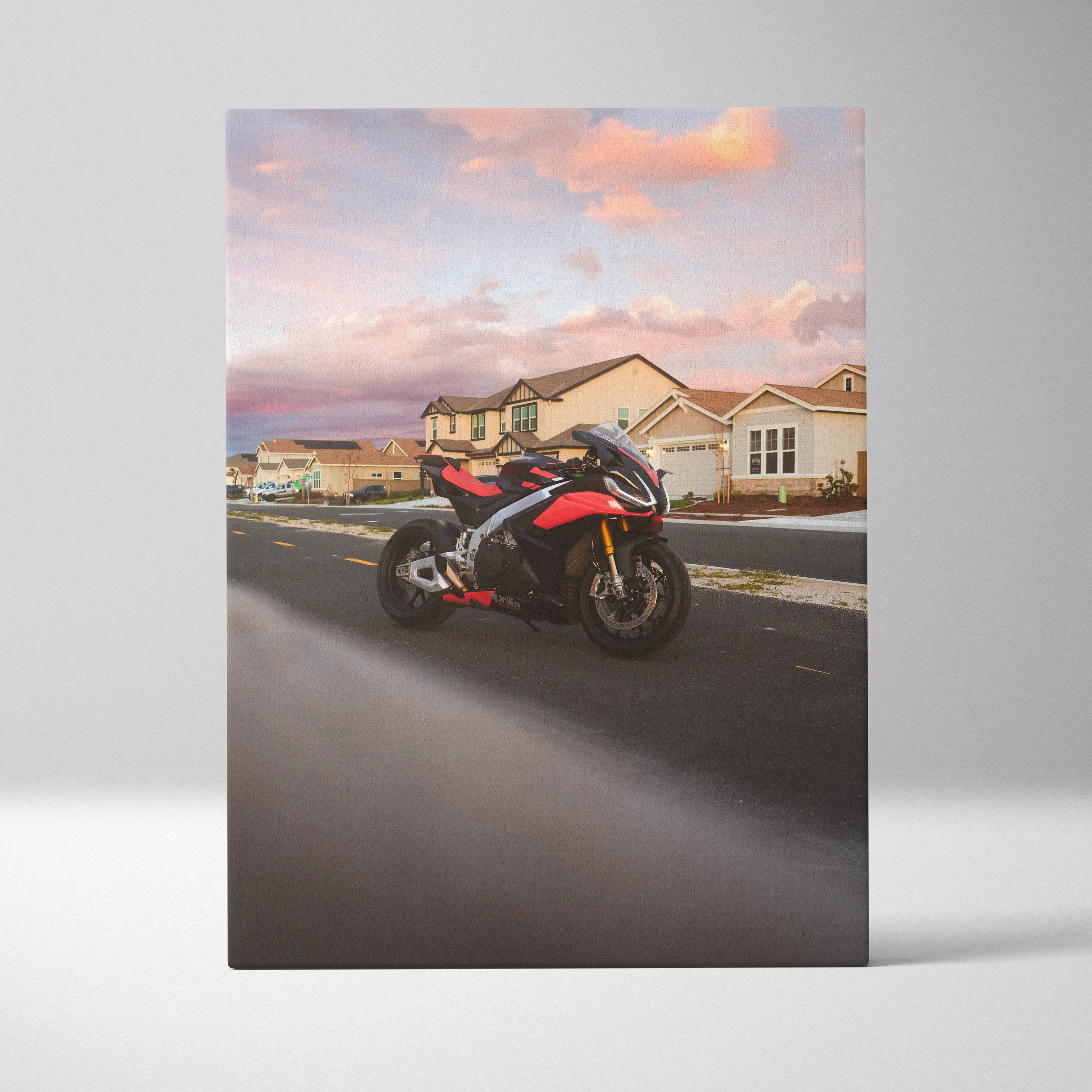 Vertical canvas wall art featuring an Aprilia RSV4 1100 Factory motorcycle at sunset on a suburban street.