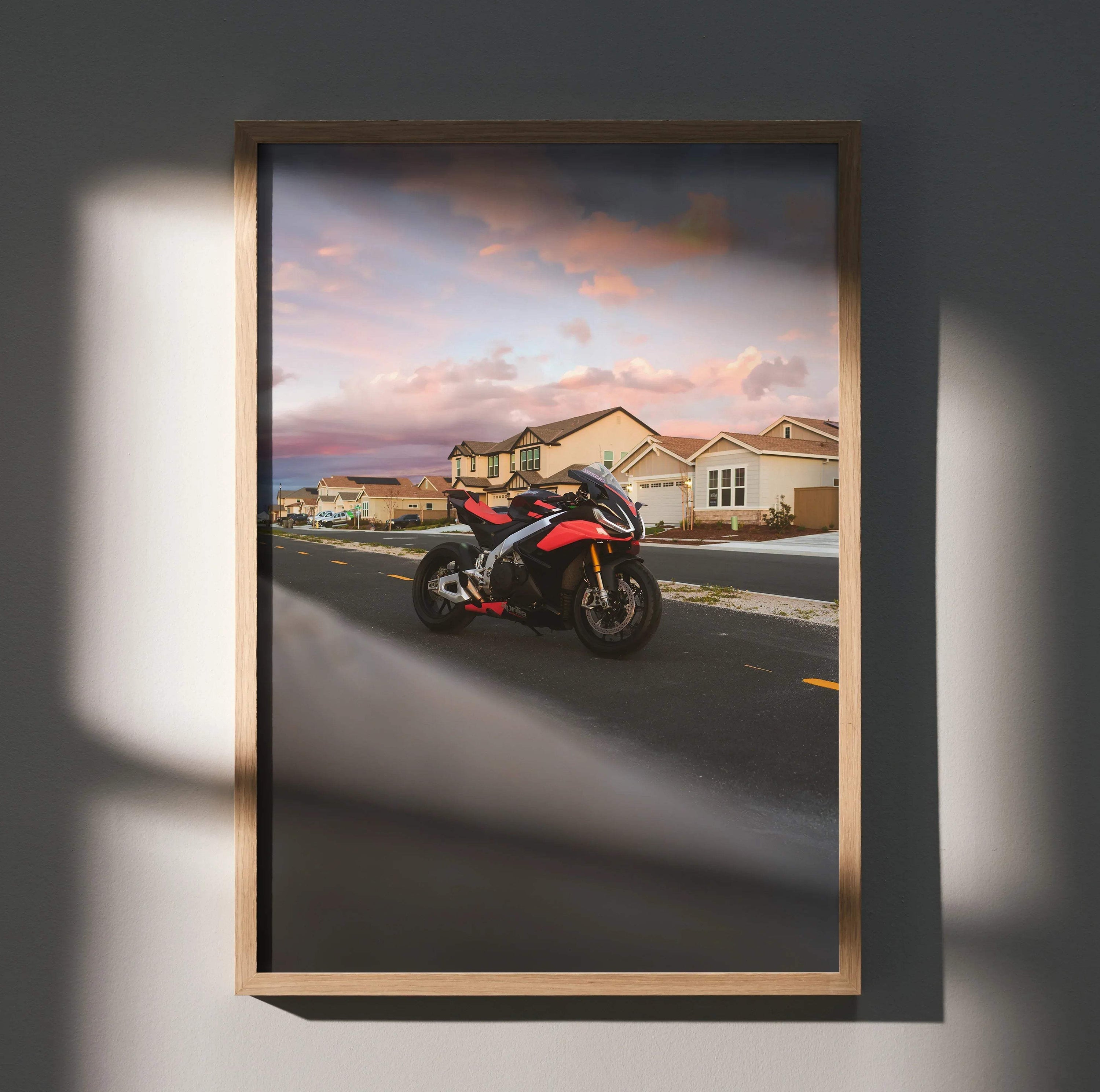 Aprilia RSV4 1100 Factory motorcycle poster with sunset sky, modern houses, and warm lighting wall art.