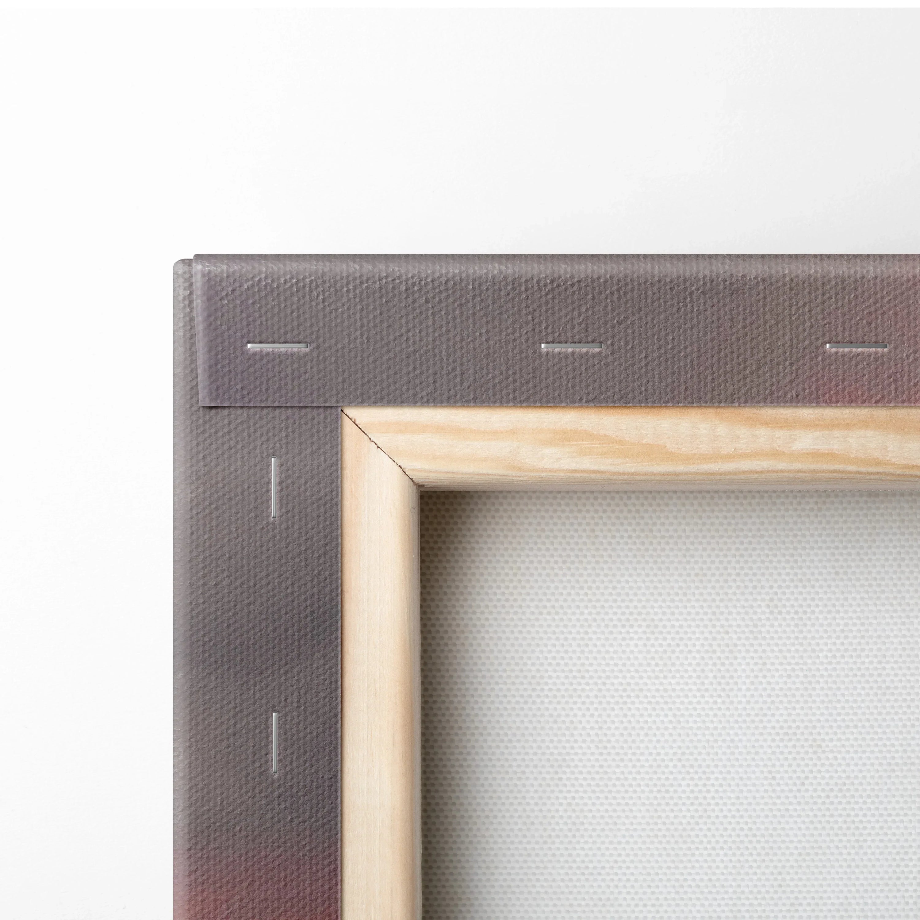 Close-up of wooden stretcher frame corner with gray canvas wrapped and stapled, wall art background.