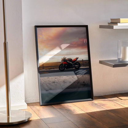 Aprilia RSV4 1100 Factory motorcycle poster with sunset sky, black frame wall art leaning on floor.