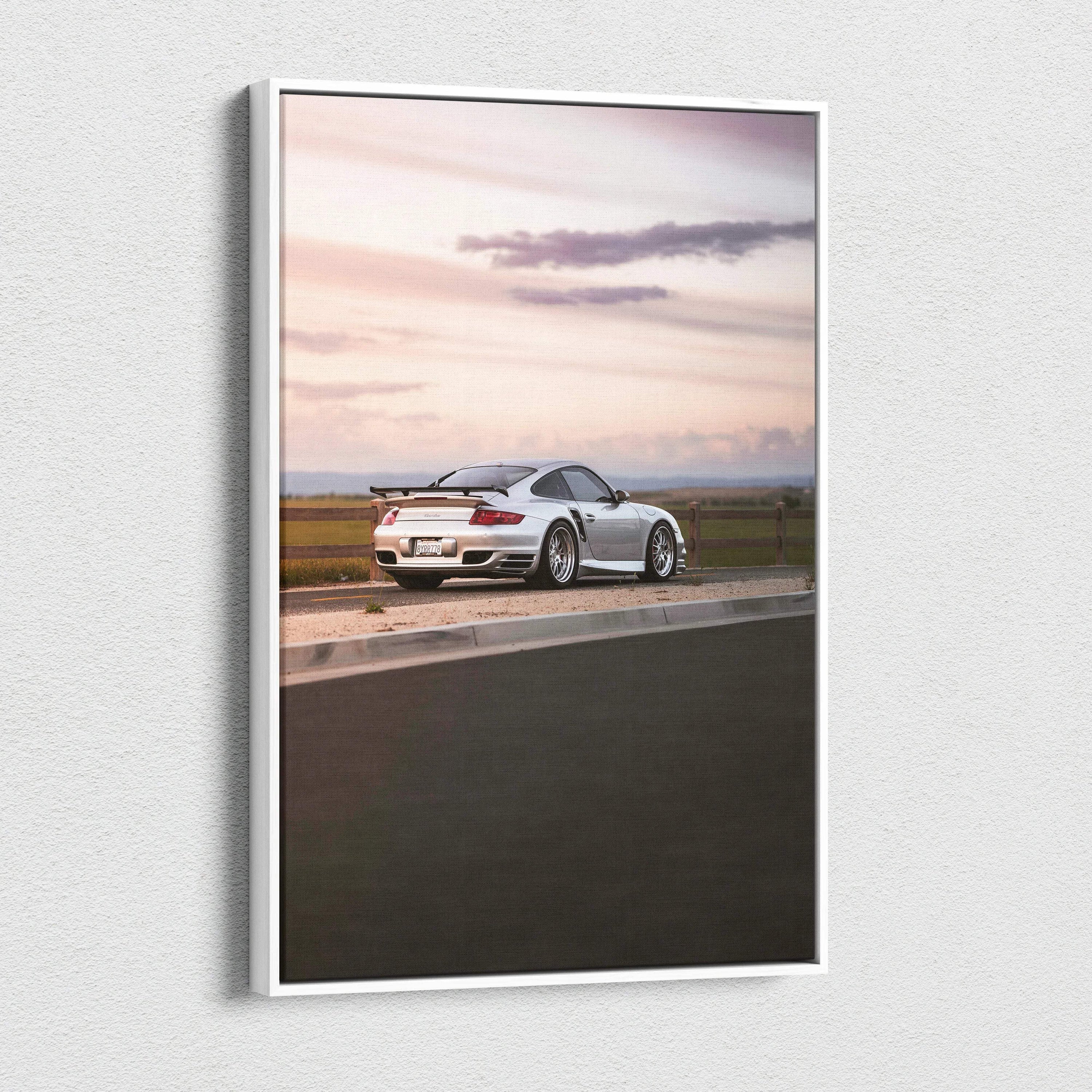 Vertical canvas wall art featuring a white Porsche 911 Turbo at sunset on a racetrack.
