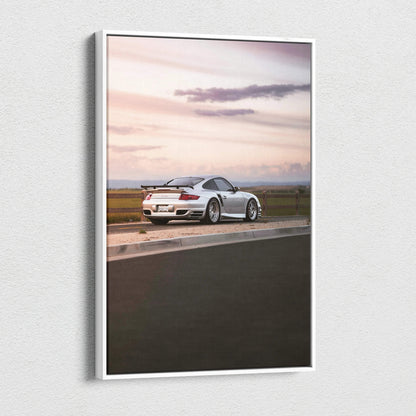 Vertical canvas wall art featuring a white Porsche 911 Turbo at sunset on a racetrack.