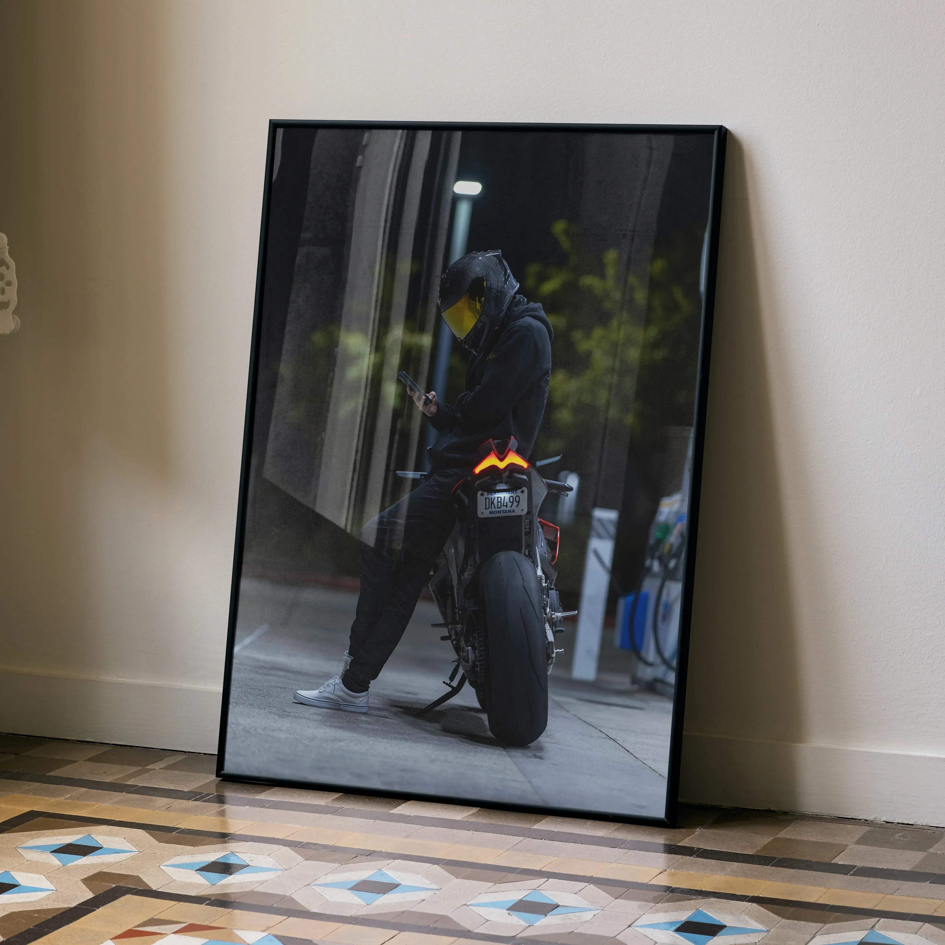 Black-framed photographic print of a motorcyclist in dark gear with yellow scorpion r1 helmet on aprilia rsv4 at night