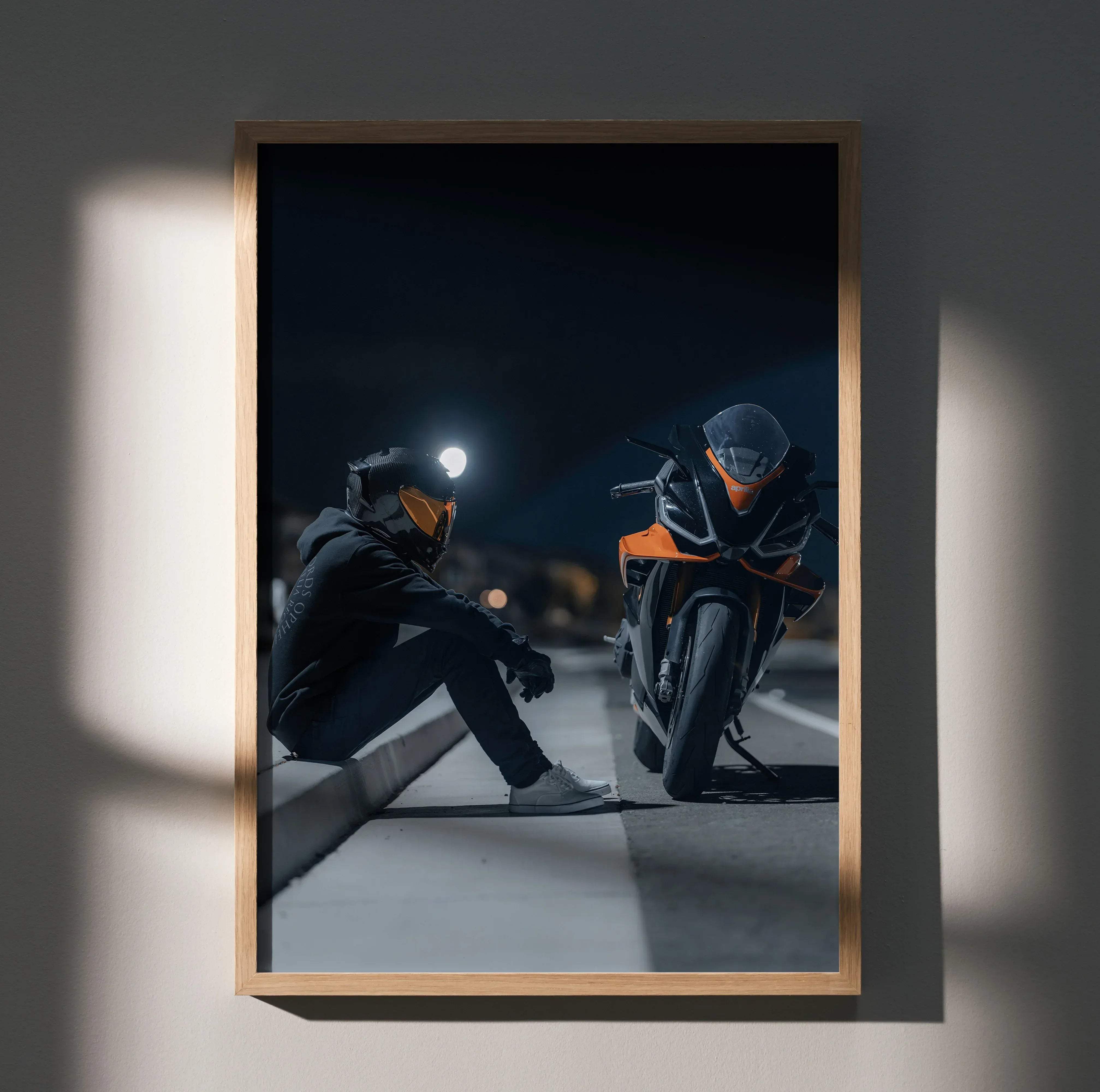 A framed biker poster featuring a black and orange Aprilia RSV4 motorcycle with a scorpion R1 helmet and seated male