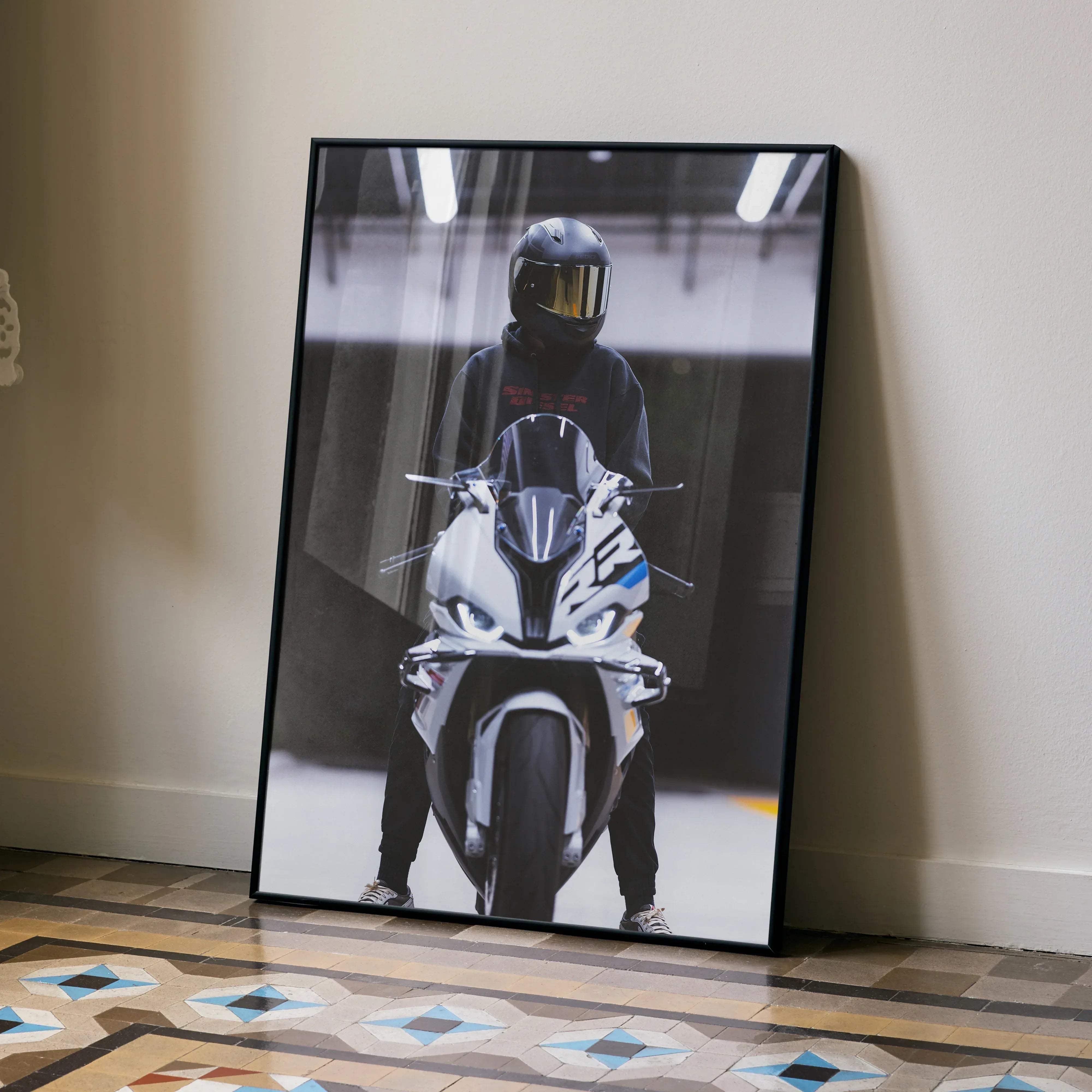 Black-framed biker poster featuring a male with a black Shoei RF1200 helmet standing beside a white and blue BMW S1000RR motorcycle with glowing headlights