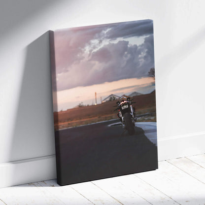 Vertical canvas wall art featuring a motorcycle on a racetrack under a cloudy sky at sunset.