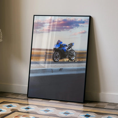 YZF-R1 motorcycle poster wall art featuring blue Yamaha bike against sunset sky, framed and leaning on floor.