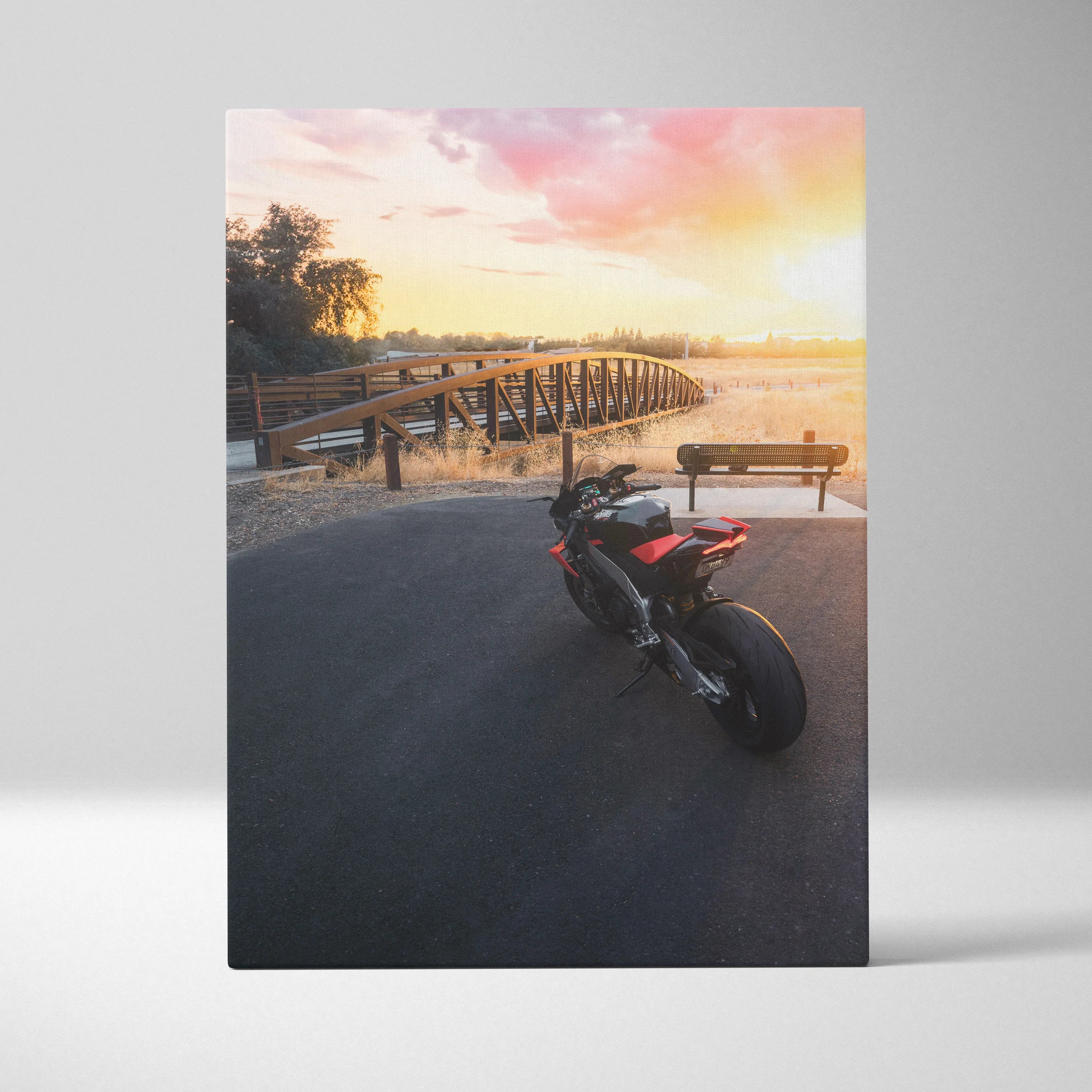 Aprilia RSV4 1100 Factory motorcycle at sunset on canvas wall art with warm sky and wooden pier background.