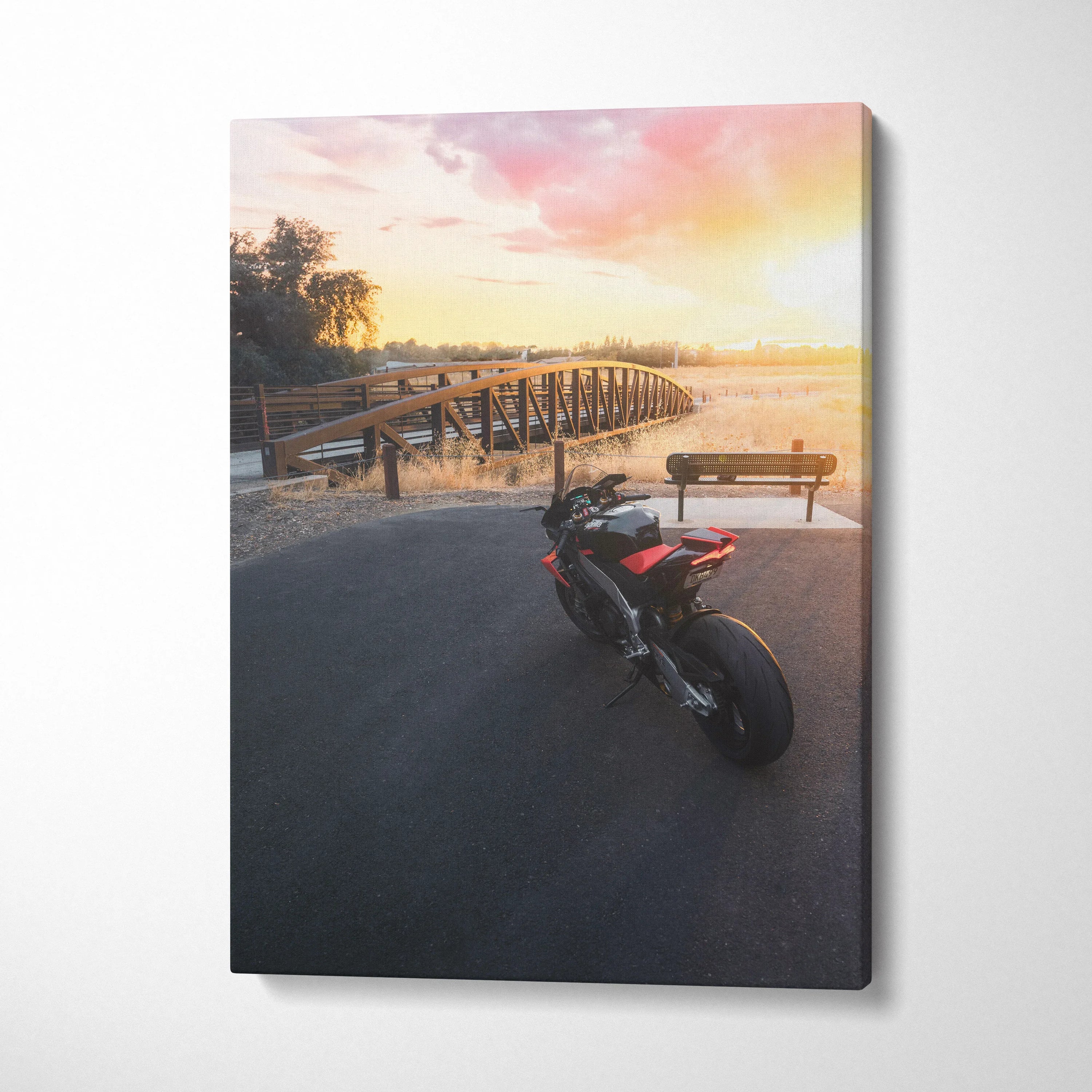 Vertical canvas wall art featuring Aprilia RSV4 1100 Factory motorcycle at sunset by a wooden bridge.
