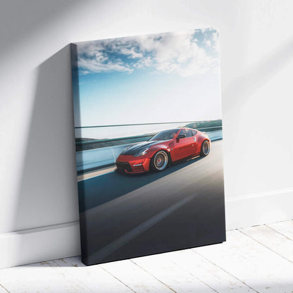 Red Nissan 370z speeding on highway canvas wall art with blue sky background.