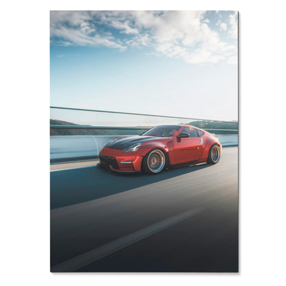 Red Nissan 370Z sports car driving on road under blue sky poster wall art.