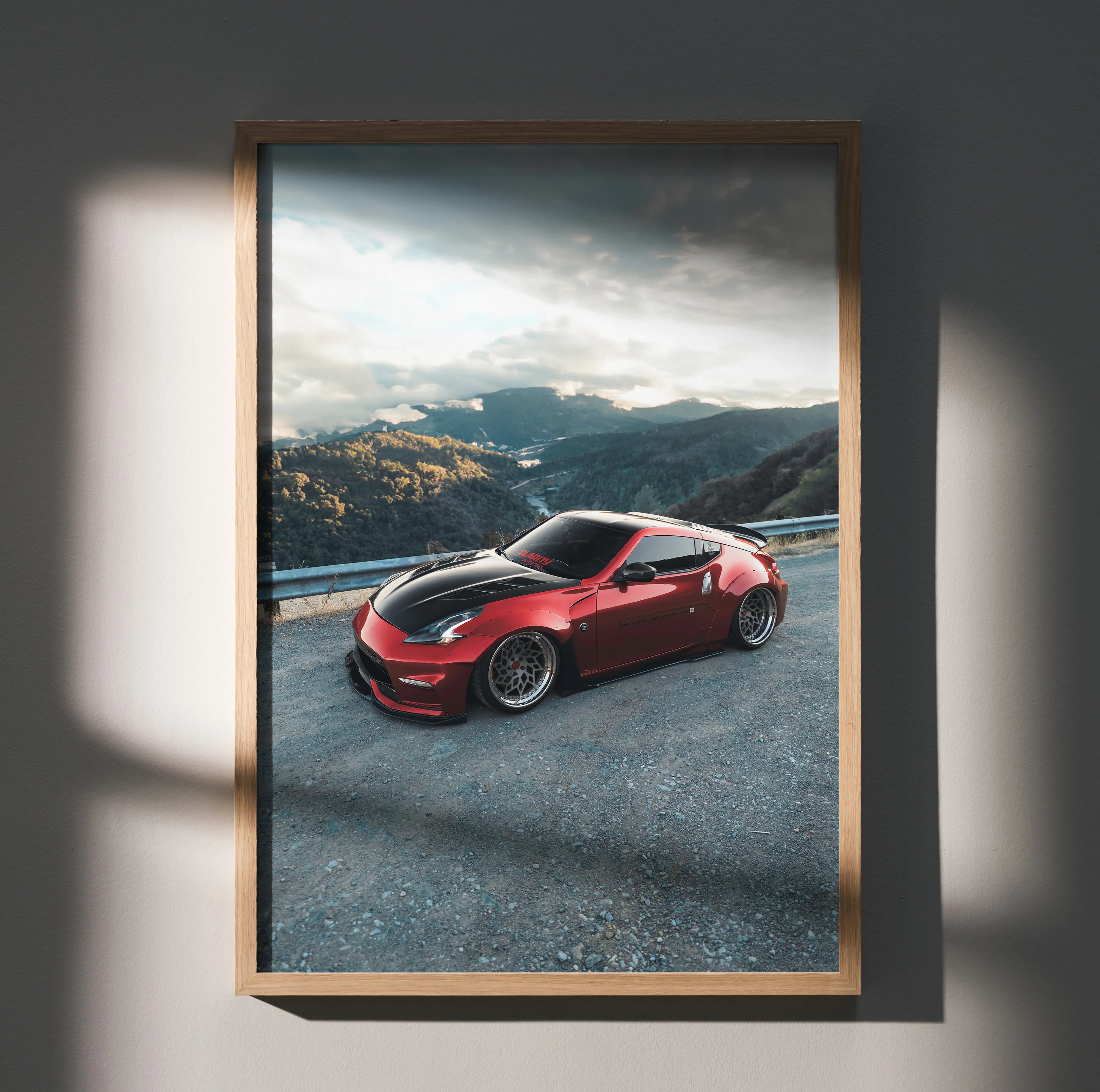 Red Nissan 370Z sports car wall art poster with mountain landscape background in a wooden frame.
