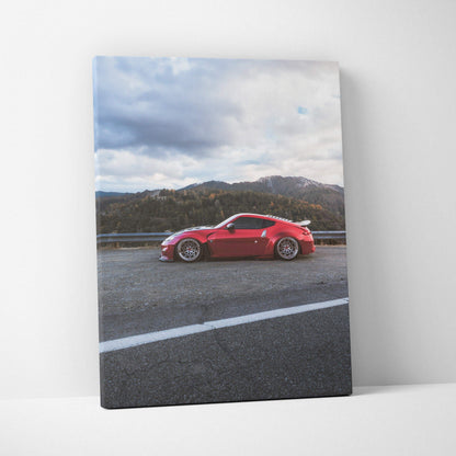 Red Nissan 370z car on road with mountains and cloudy sky backdrop vertical canvas wall art.