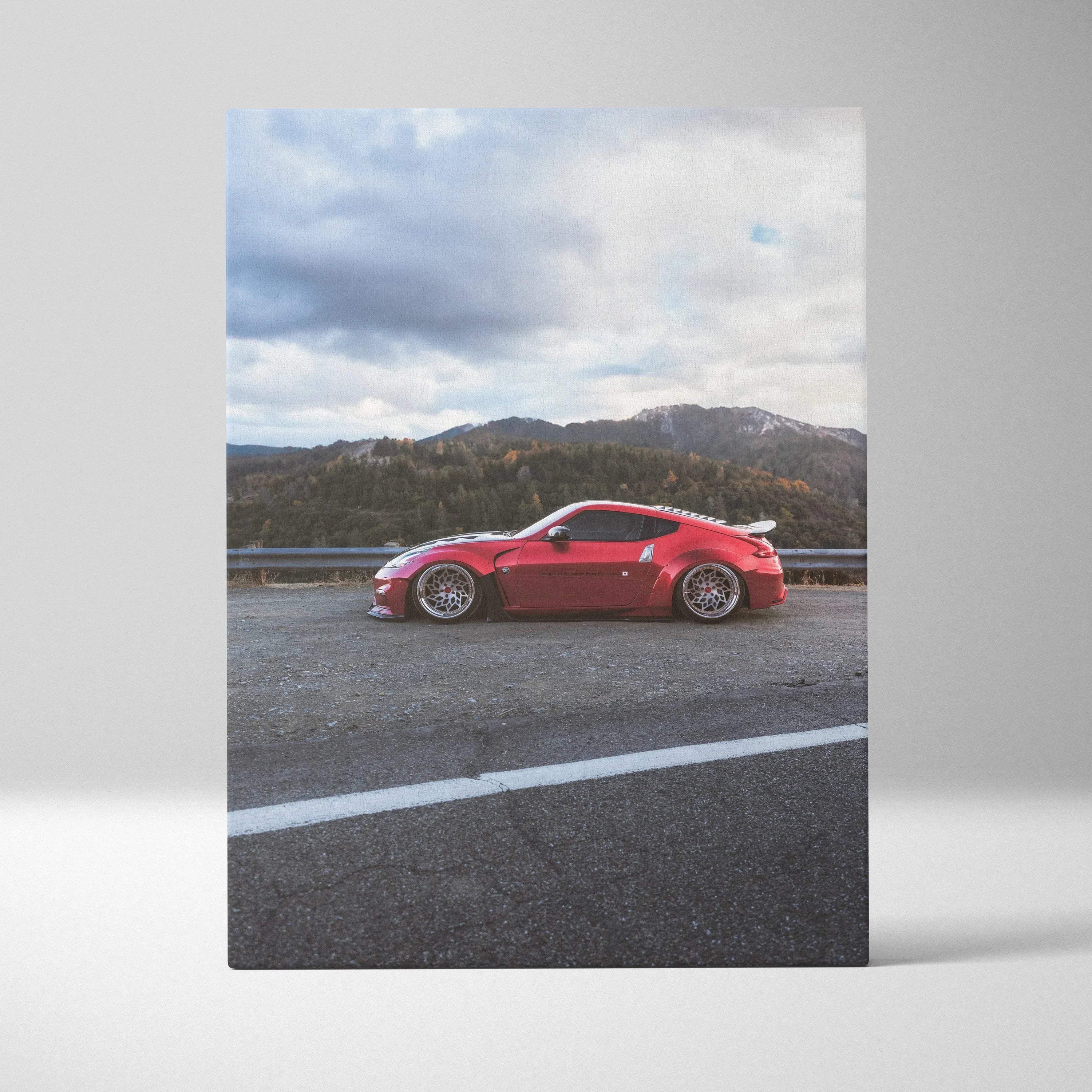 Red Nissan 370z on mountain road vertical canvas wall art with cloudy sky background.