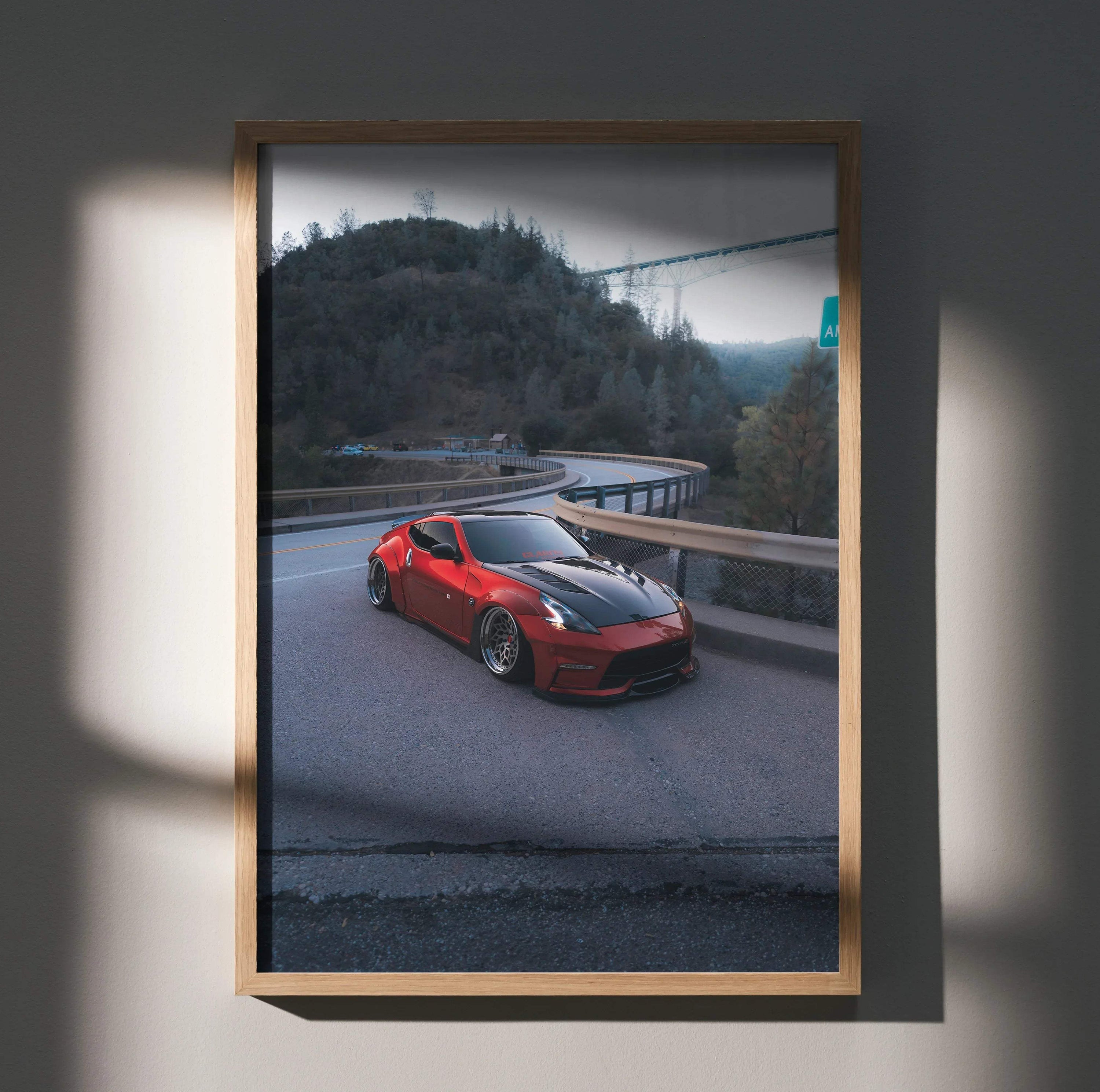 Red Nissan 370z parked on mountain road poster wall art in wooden frame.