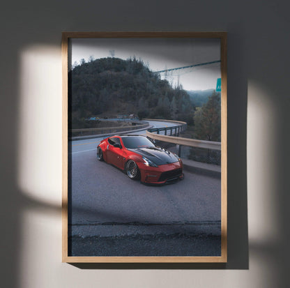 Red Nissan 370z parked on mountain road poster wall art in wooden frame.