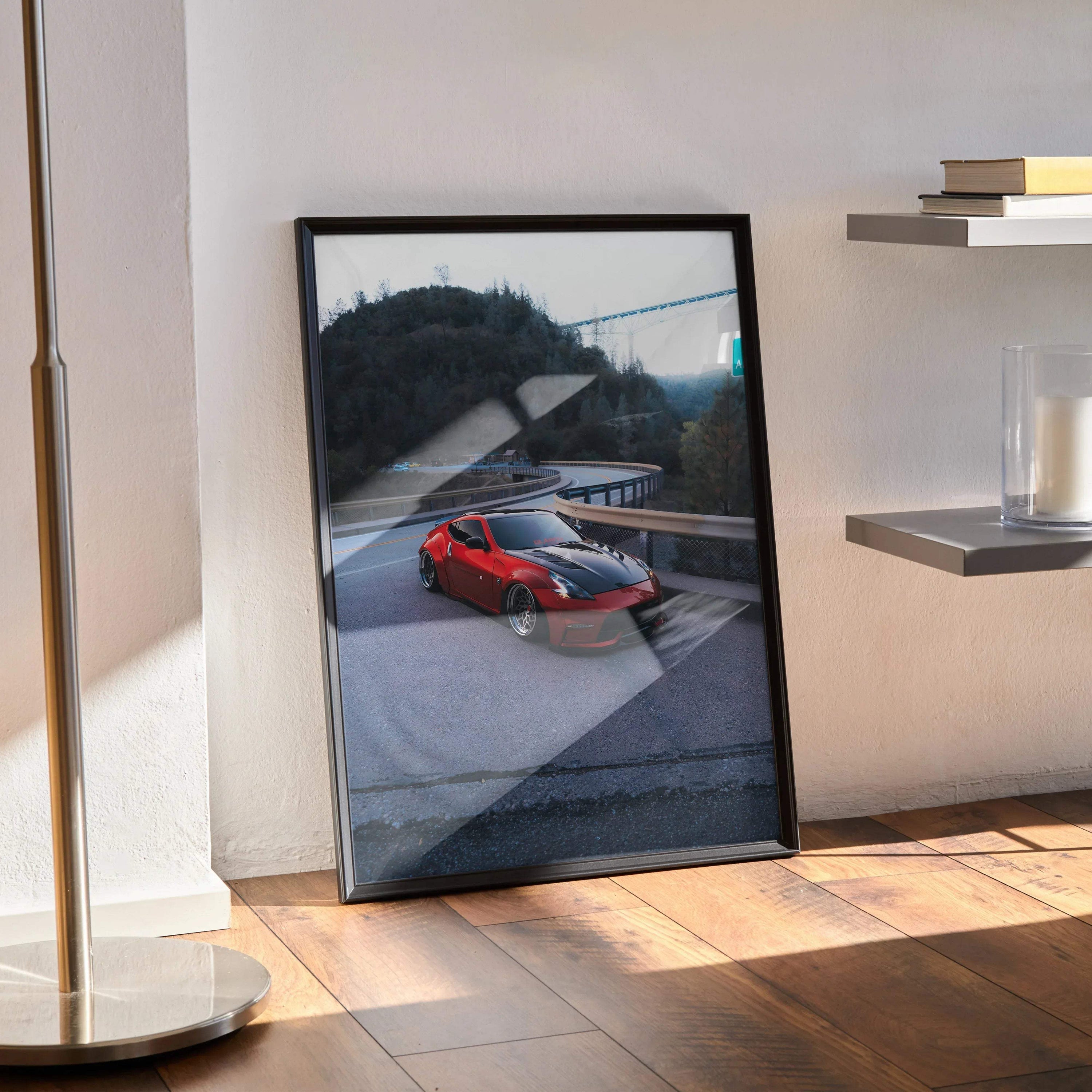 Nissan 370z poster wall art in black frame leaning on floor with modern shelving and sunlight.