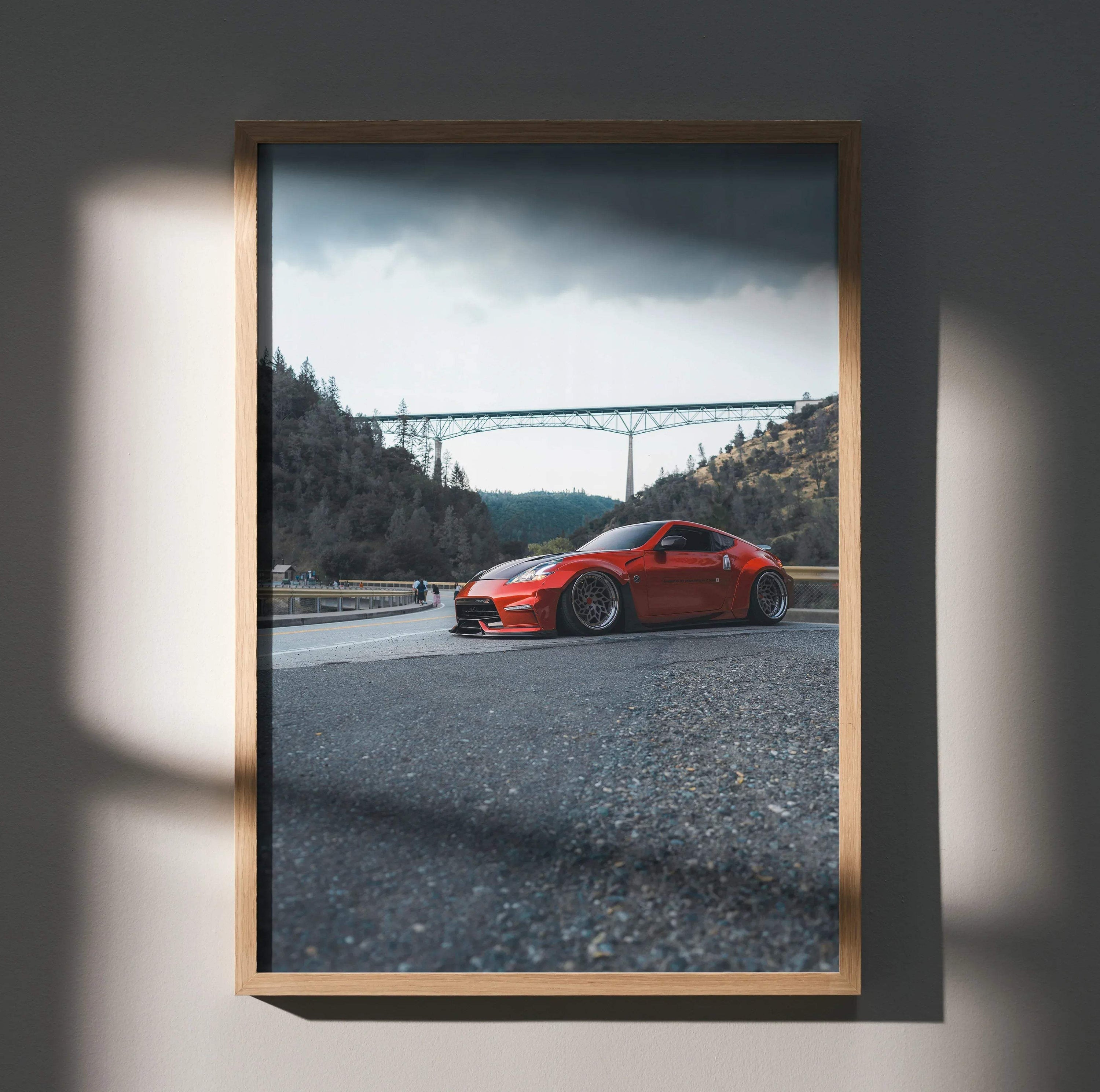 Nissan 370Z red sports car on gravel with mountain bridge background poster wall art.