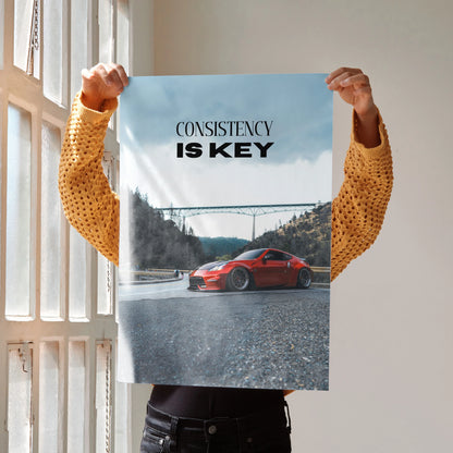 Motivational poster wall art with red Nissan 370z and "Consistency Is Key" text on sky background.
