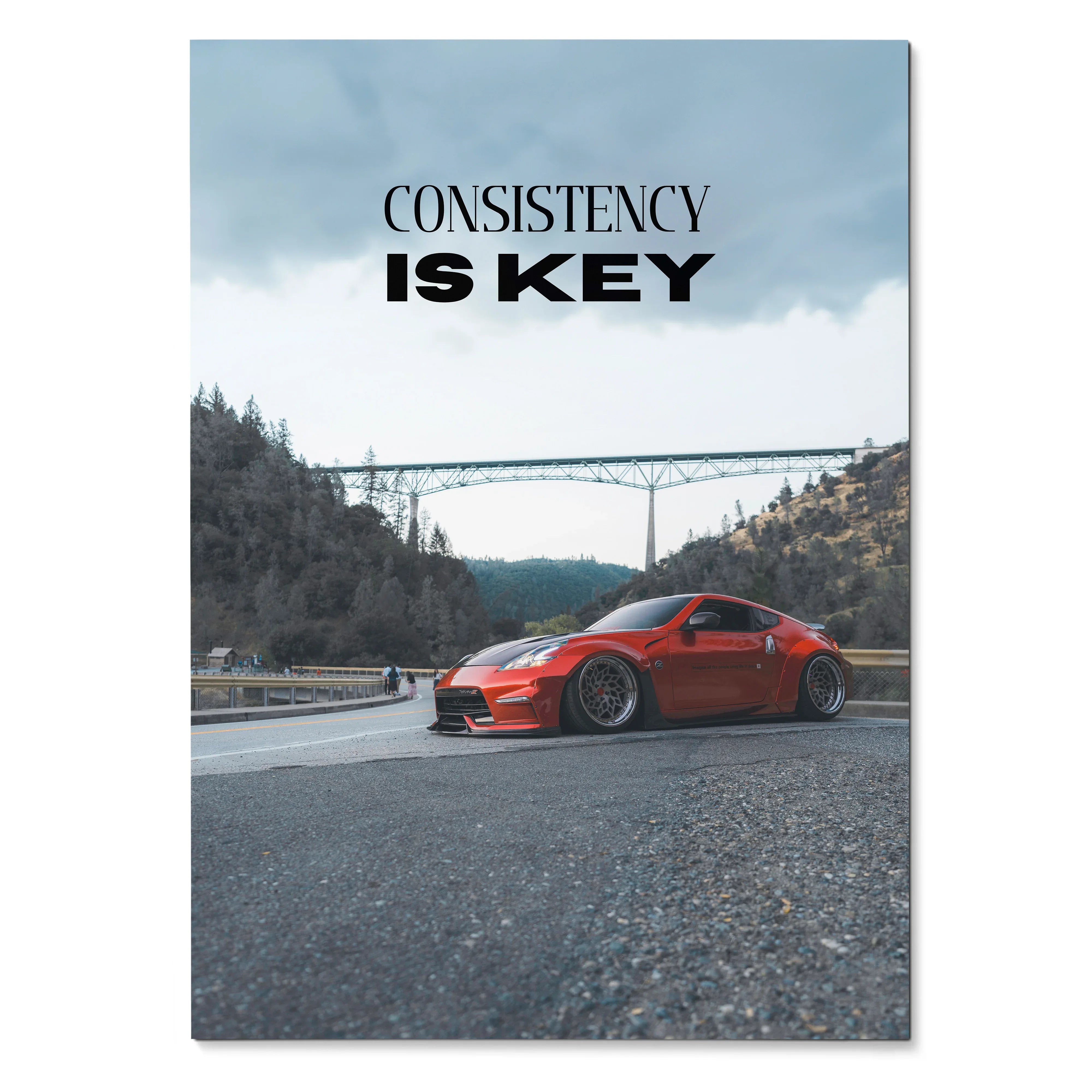 Motivational poster wall art featuring a red Nissan 370z with "Consistency is Key" text and scenic bridge background.