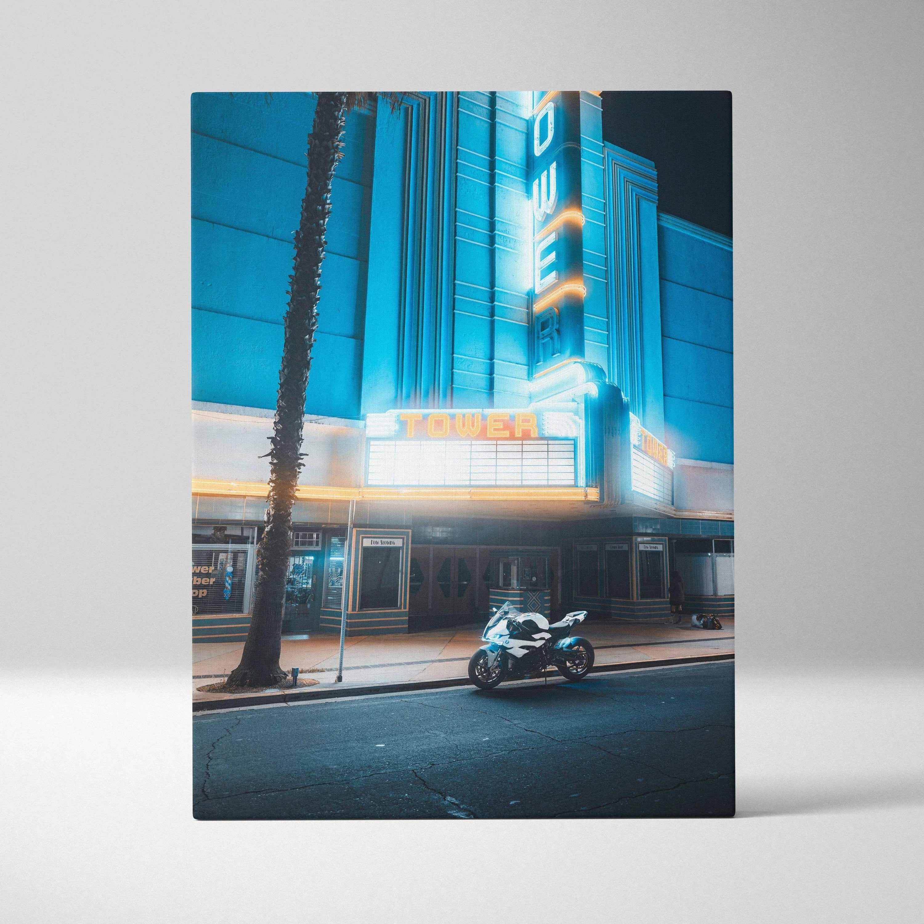 Vertical canvas wall art of a BMW S1000RR motorcycle parked by a neon-lit vintage theater at night.