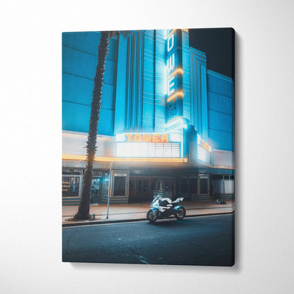 Vertical canvas wall art featuring a BMW S1000RR motorcycle parked in front of a neon-lit theater at night.
