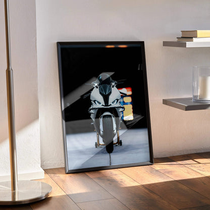 BMW S1000RR motorcycle poster wall art with sleek modern black frame on wooden floor.