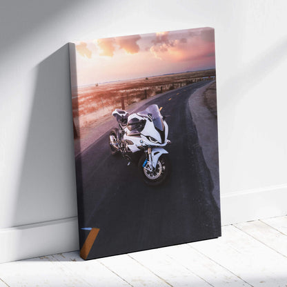 Vertical canvas wall art featuring a white BMW S1000RR motorcycle on a coastal road at sunset.