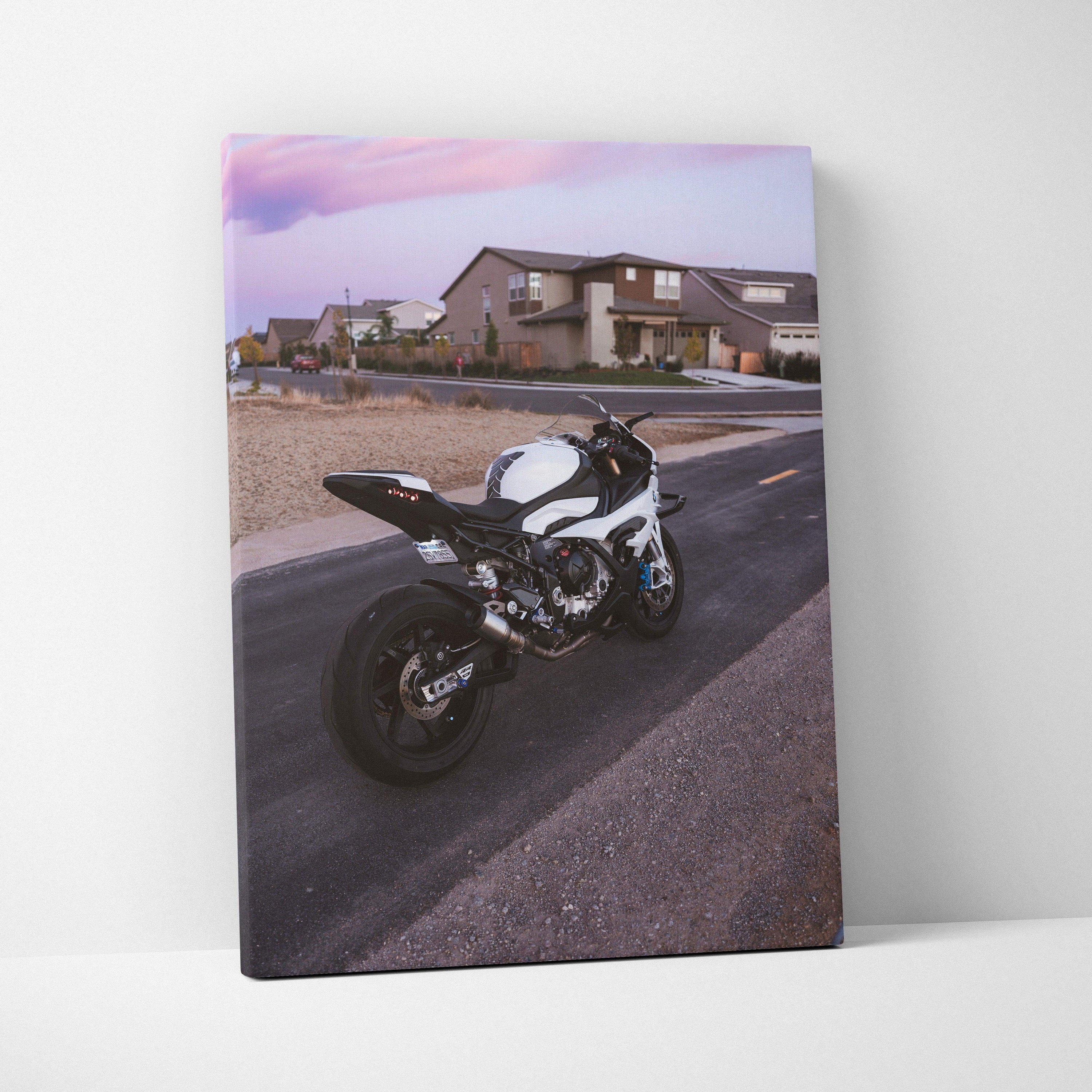 Vertical canvas wall art featuring a BMW S1000RR motorcycle parked on a suburban street at sunset.