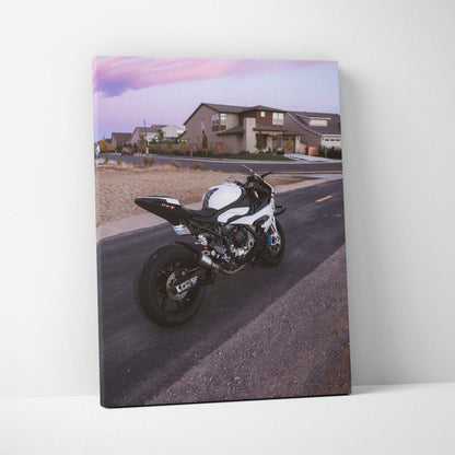 Vertical canvas wall art featuring a BMW S1000RR motorcycle parked on a suburban street at sunset.