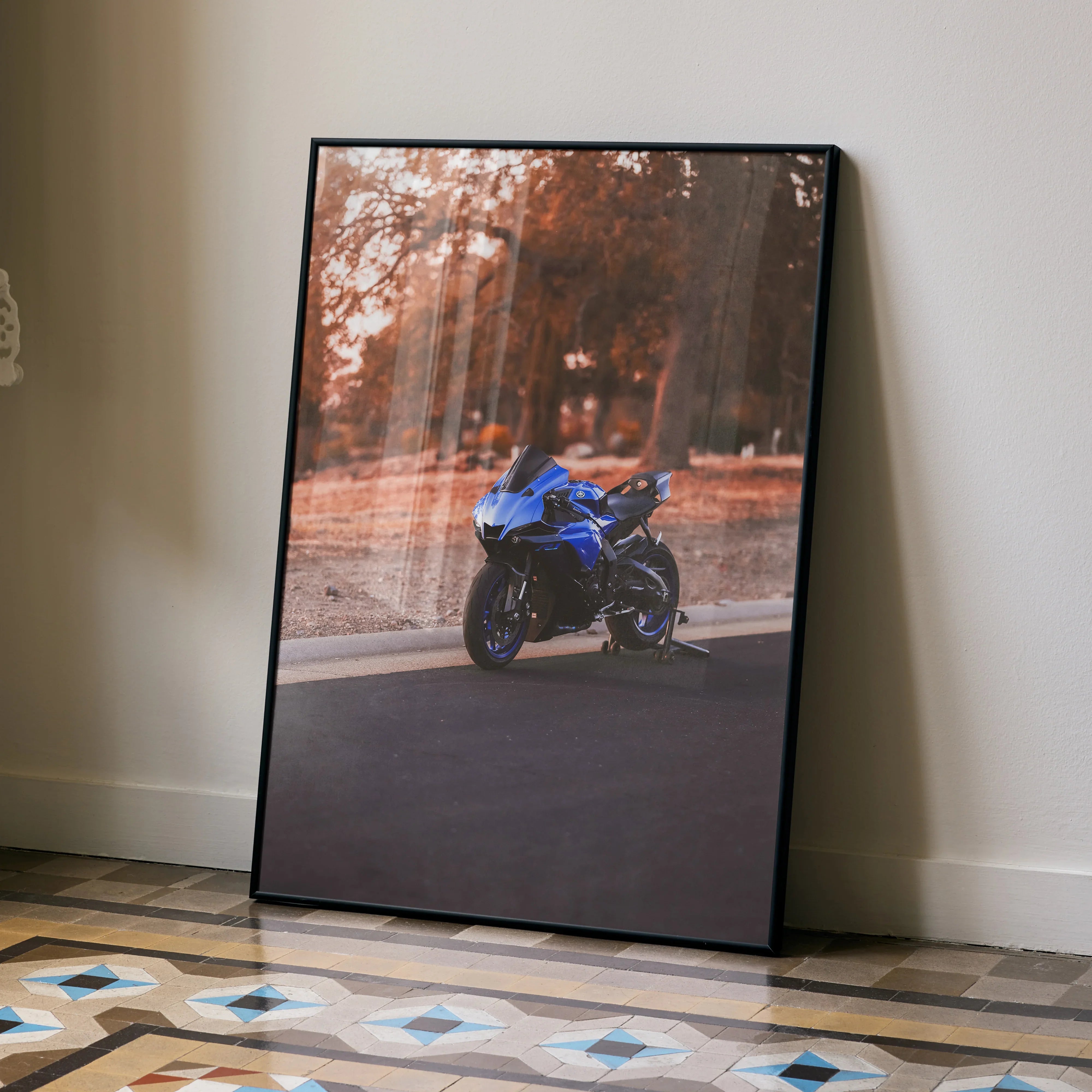 Yamaha R1 motorcycle poster with blue bike on road framed wall art leaning against beige wall.