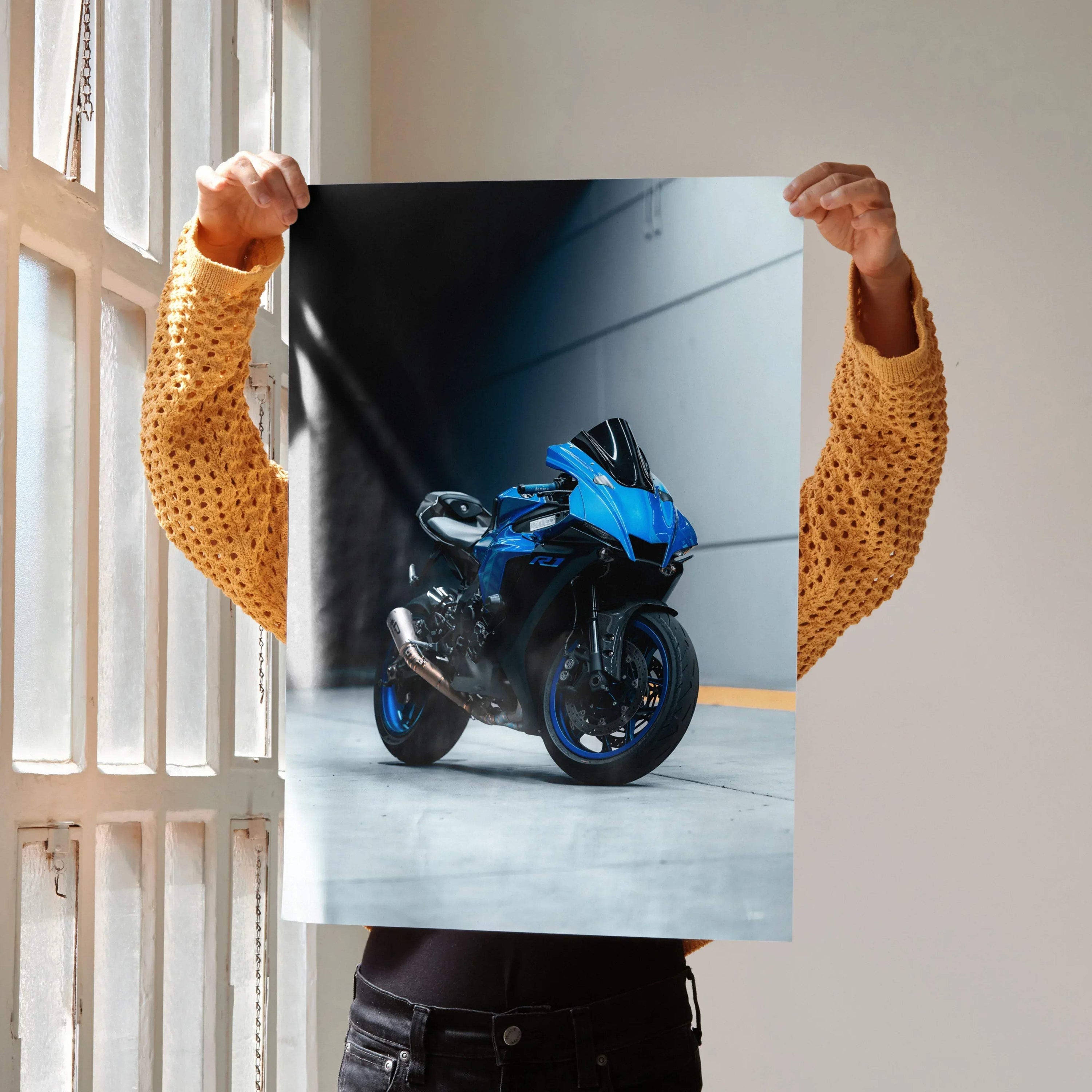 Blue Yamaha R1 motorcycle poster held against gray urban wall, sleek sportbike wall art.