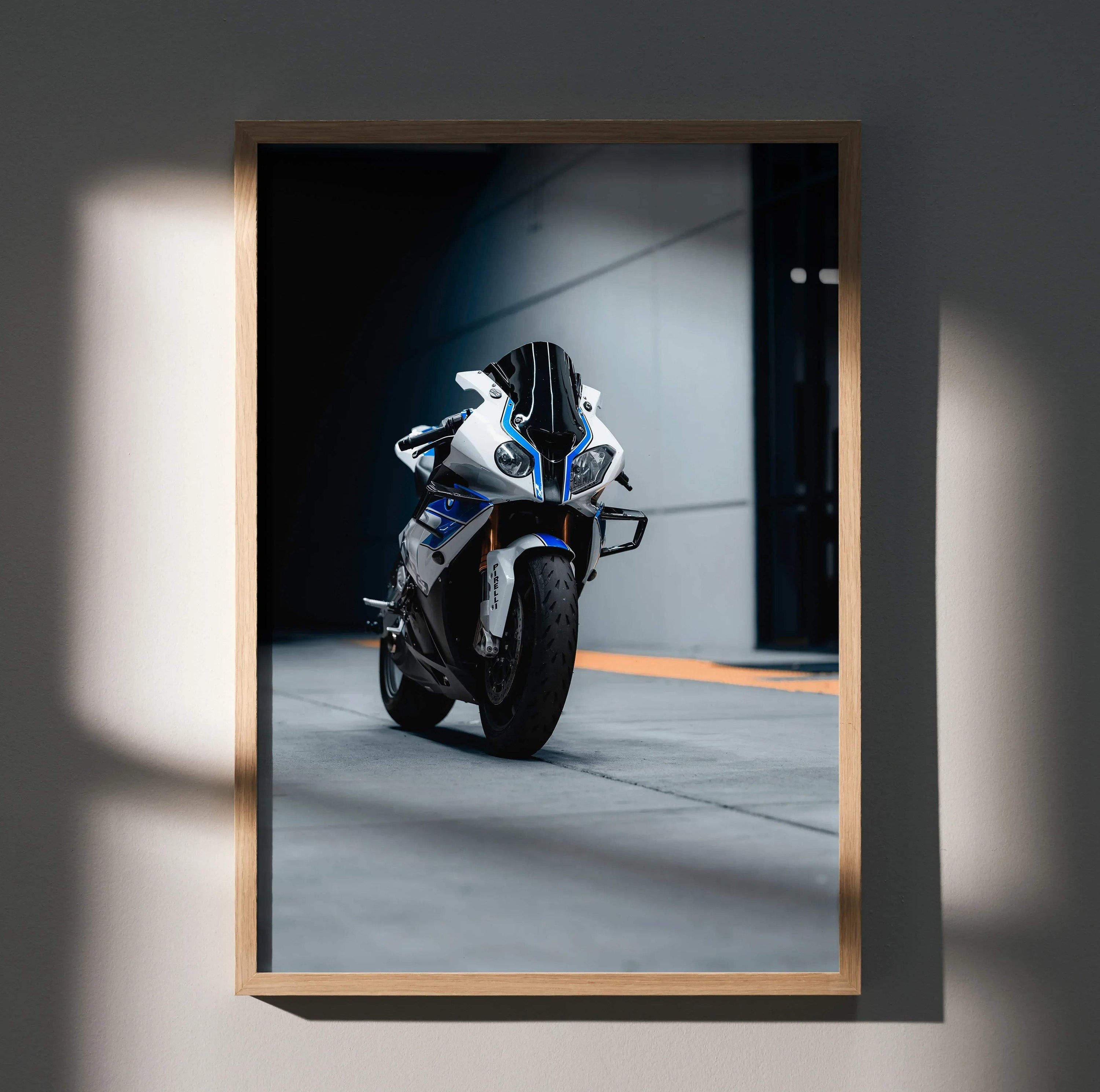 A framed photograph of a white and blue bmw s1000rr hp4 sport motorcycle with black accents in a minimalist wooden frame