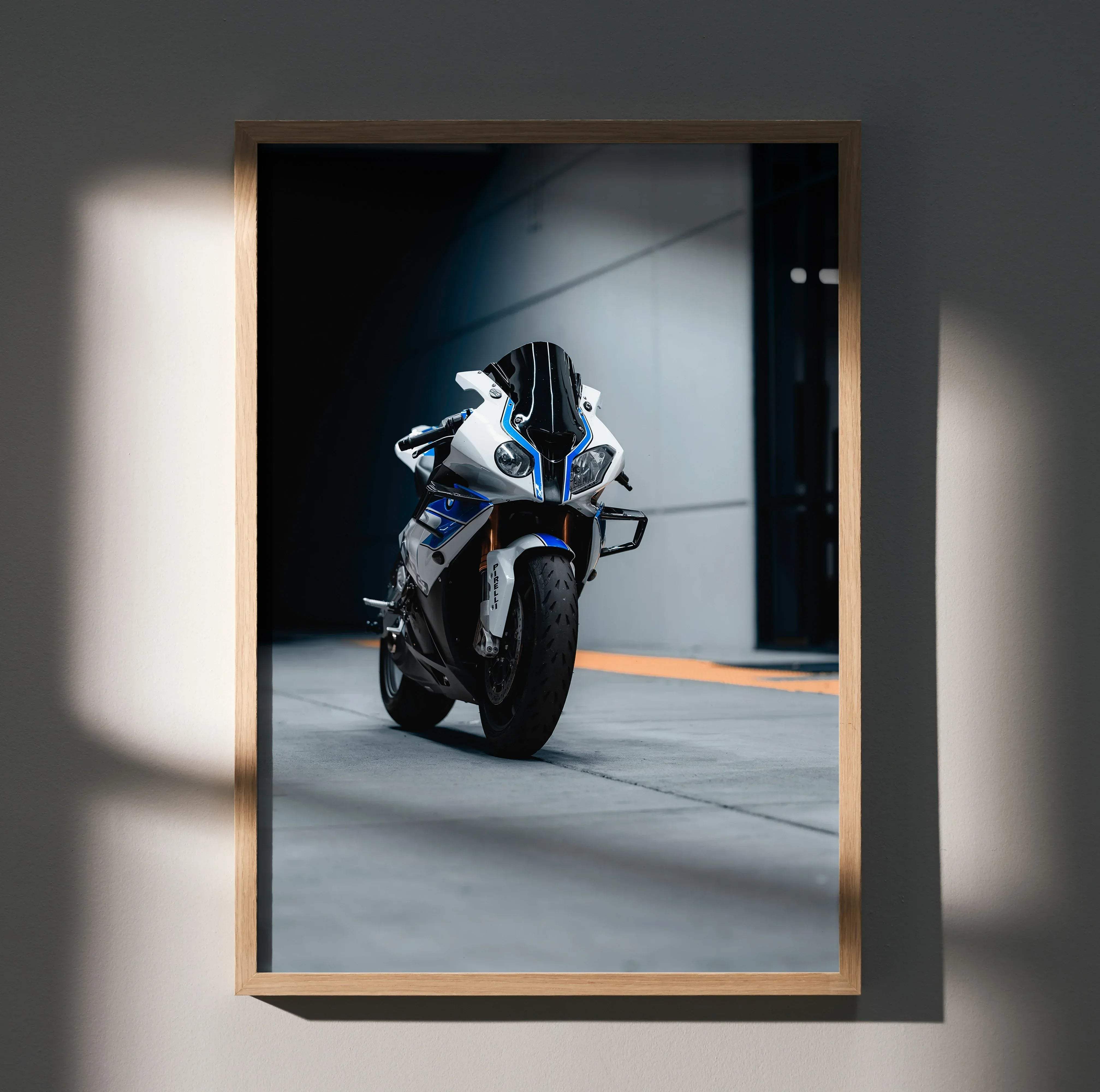 A framed photograph of a white and blue bmw s1000rr hp4 sport motorcycle with black accents in a minimalist wooden frame