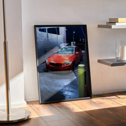 Red BMW F80 M3 poster with premium high-resolution automotive wall art in black frame leaning against wall.