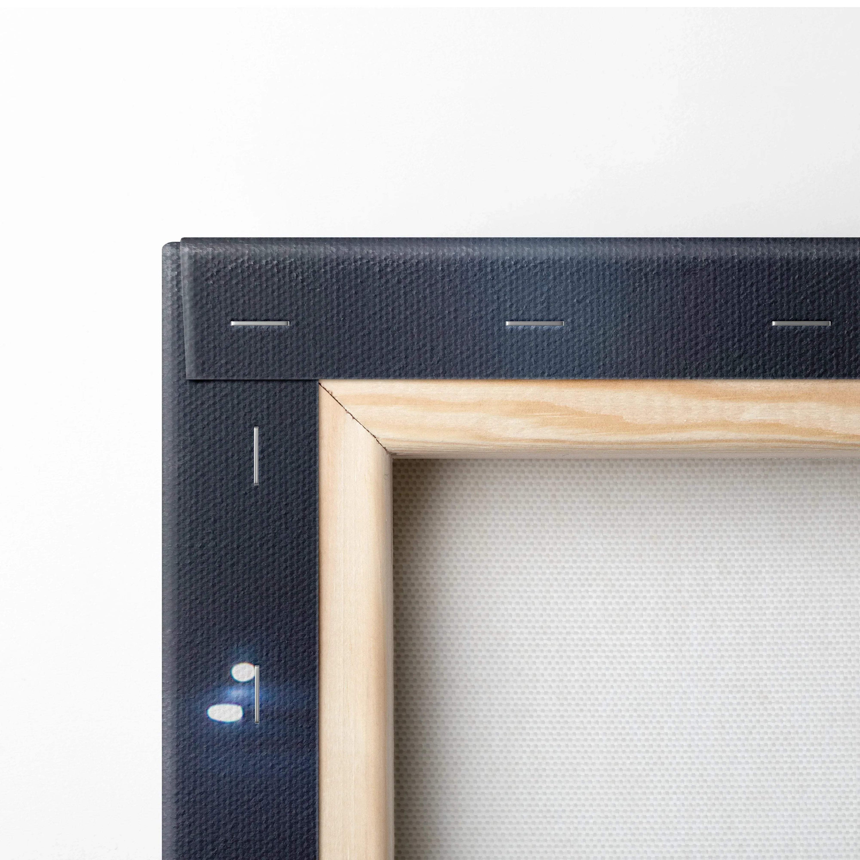 Close-up of wooden stretcher frame supporting black canvas wall art with visible staples and corner joint details.