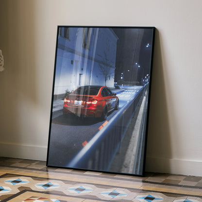 BMW F80 M3 red sports car driving at night poster framed wall art leaning on beige wall.