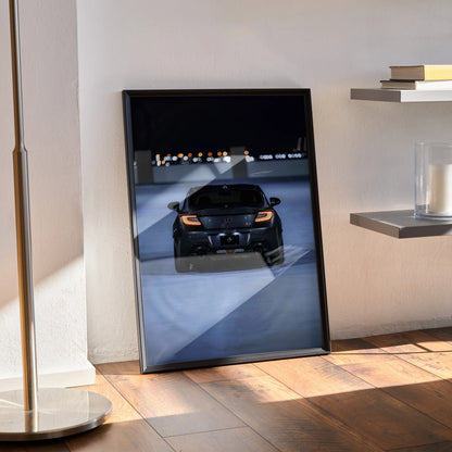 Toyota GR86 black sports car poster framed on floor, modern wall art with city lights backdrop.