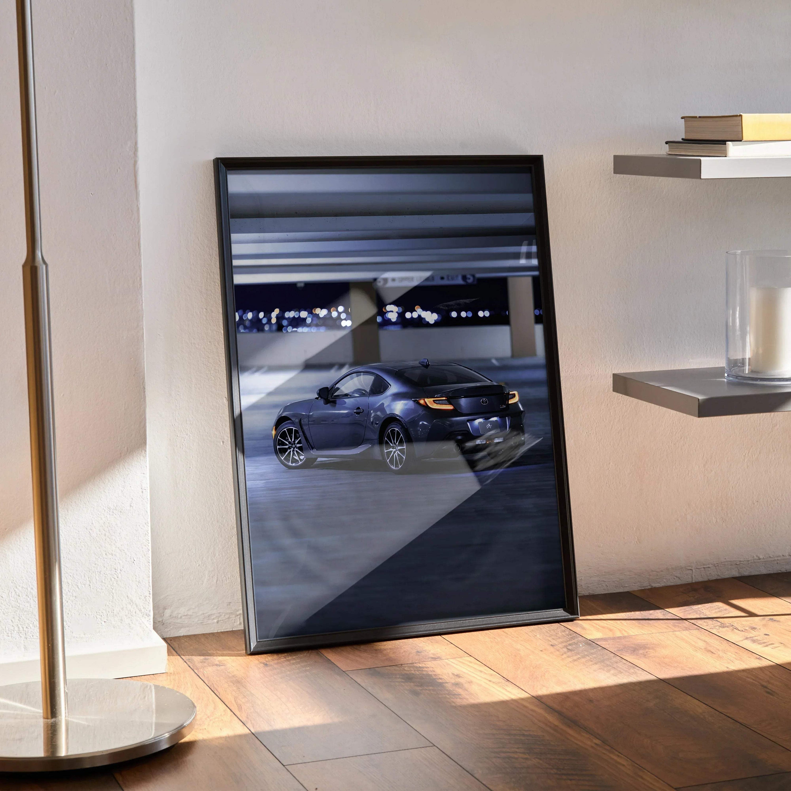 Toyota GR86 poster wall art featuring a sleek car under soft lighting in a dark setting, framed in black.