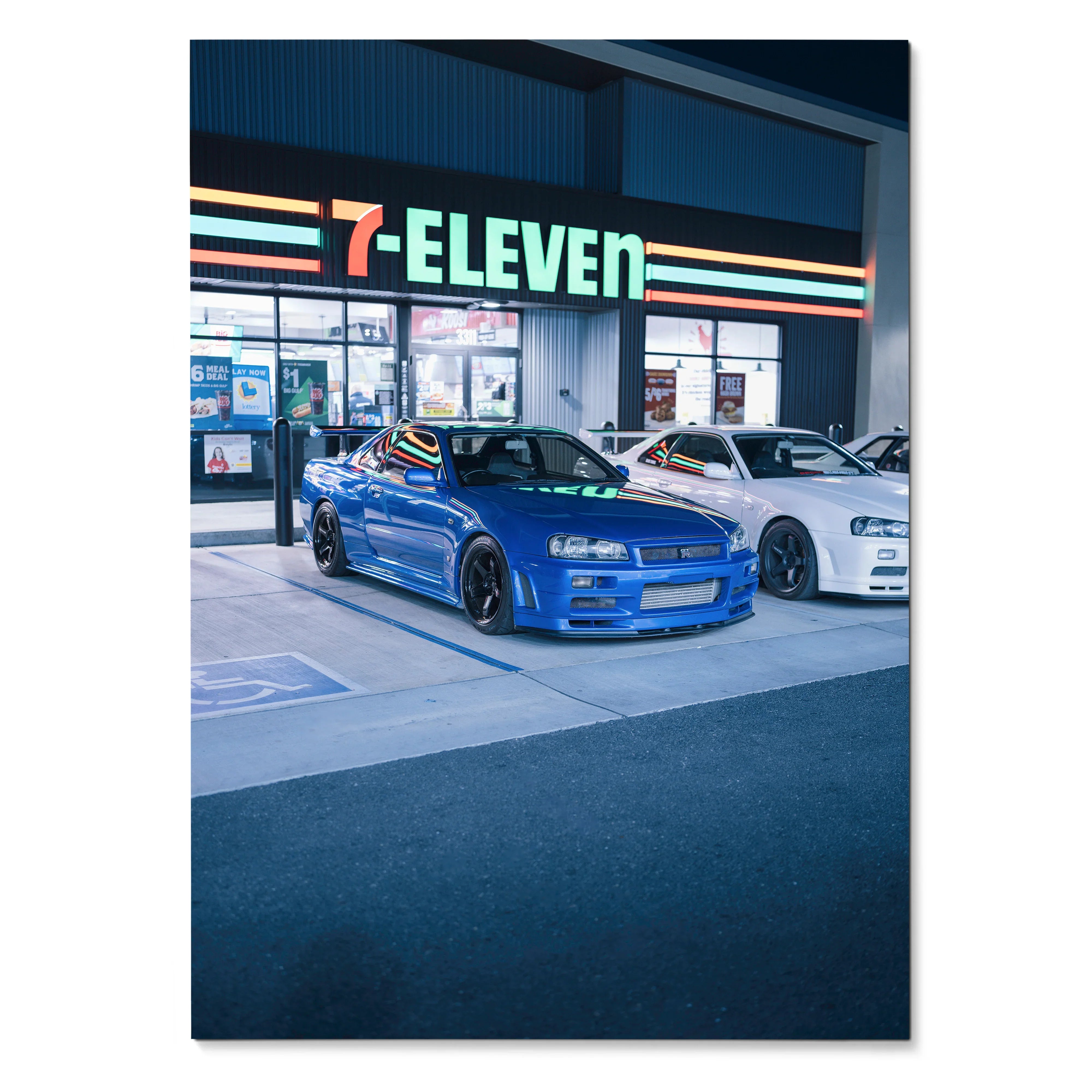 Nissan GTR R34 Skyline in blue and white parked outside 7-Eleven at night poster wall art.